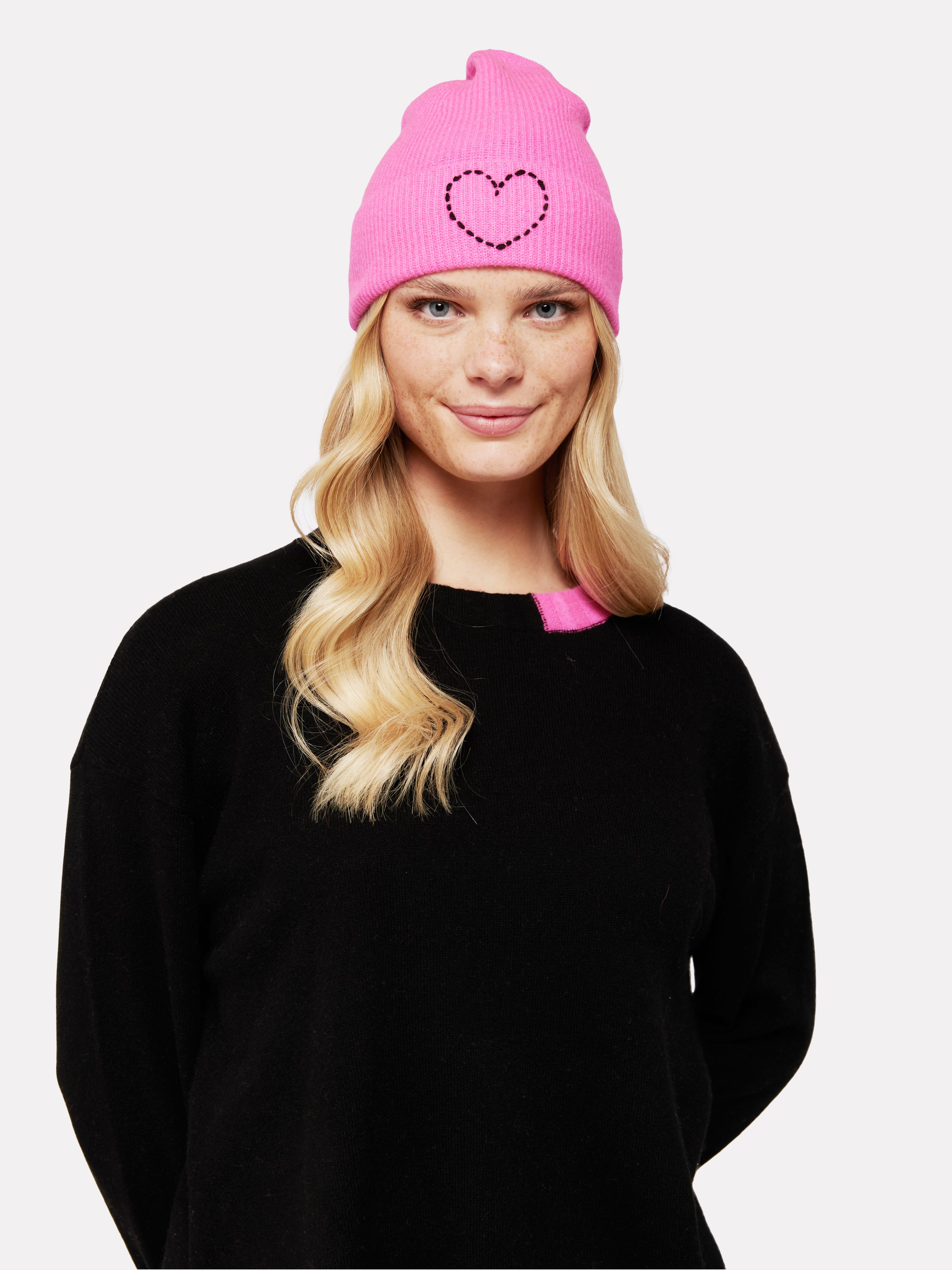 woman wearing a pink beanie hat with a black heart on