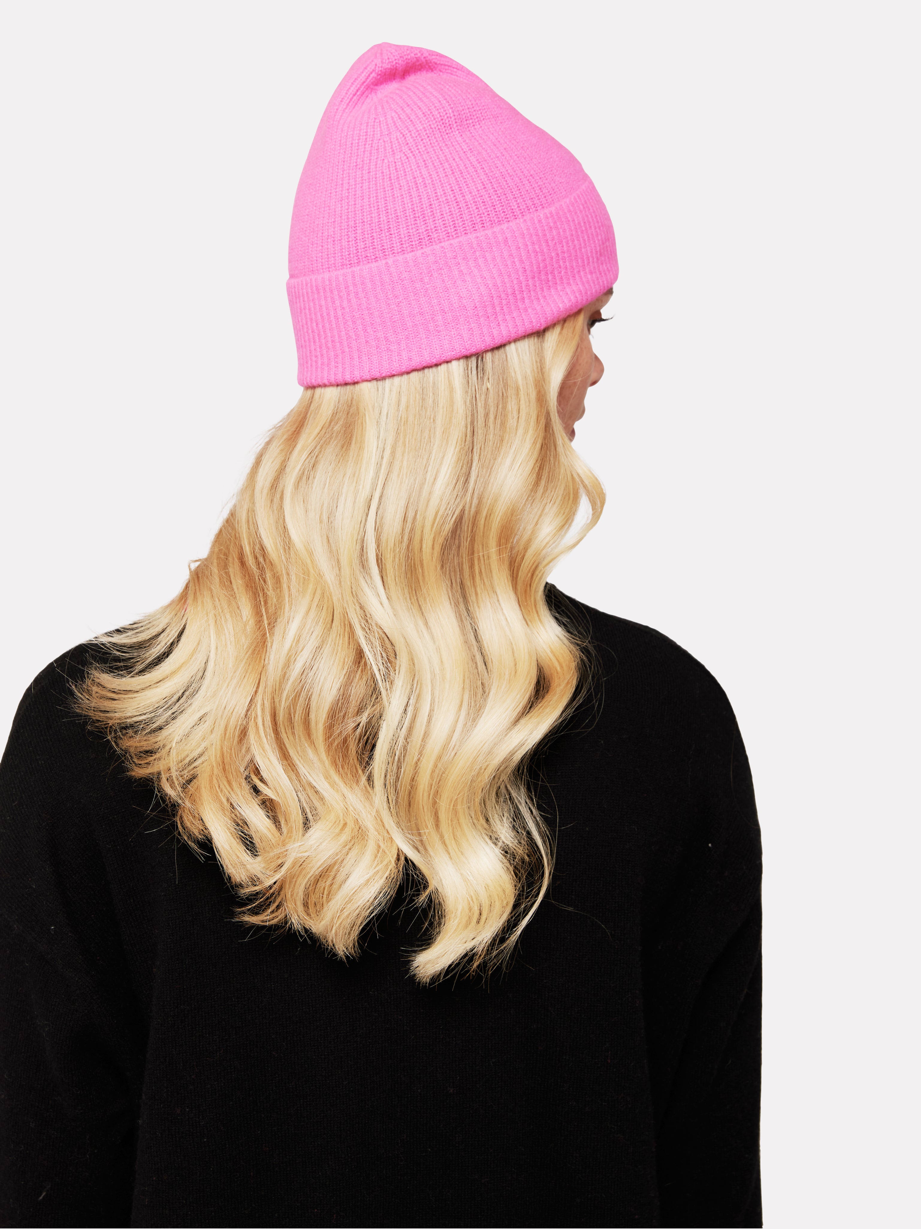 woman wearing a pink beanie hat with a black heart on