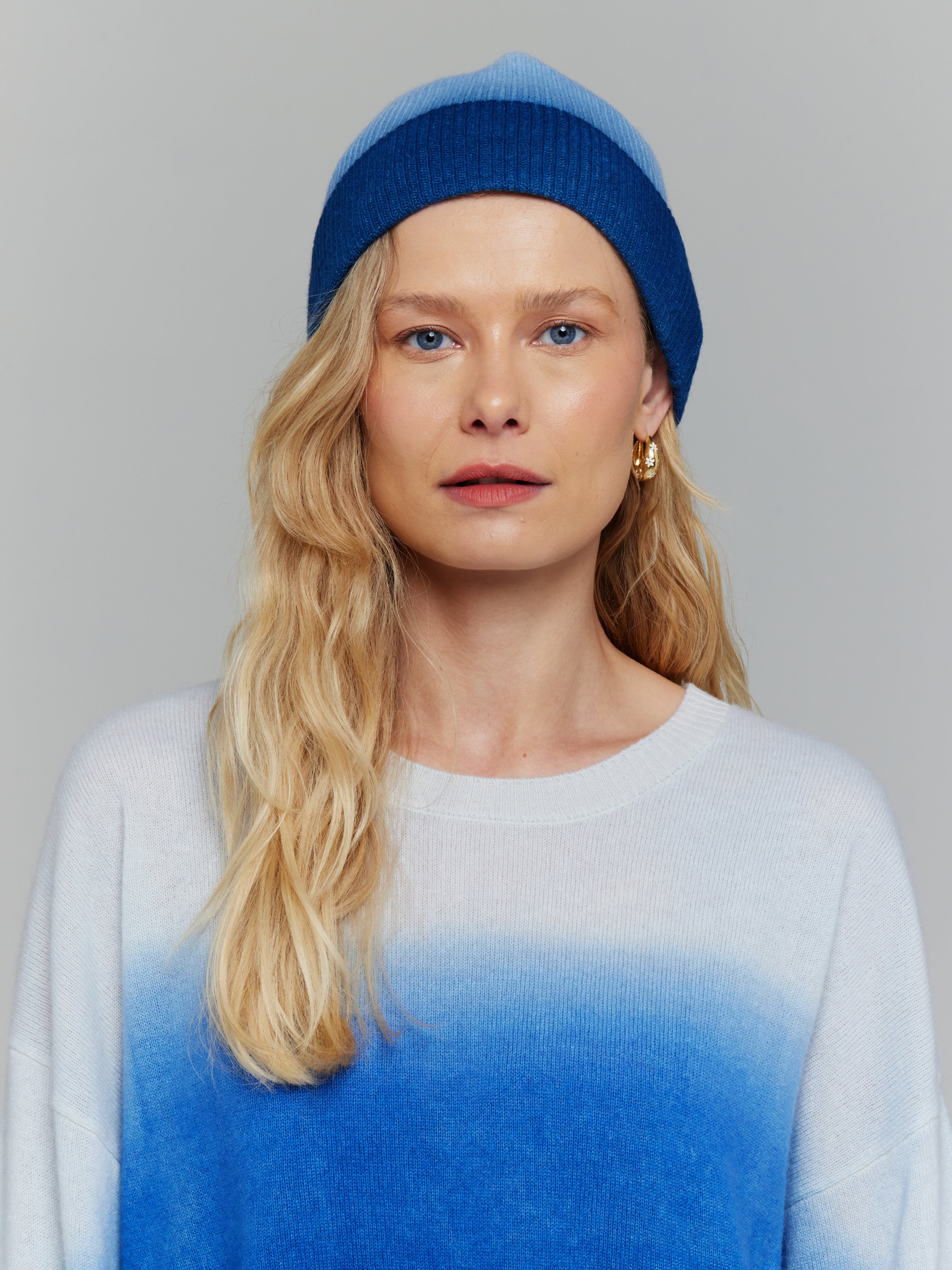 A person wearing a blue and white ombre beanie hat and matching jumper.