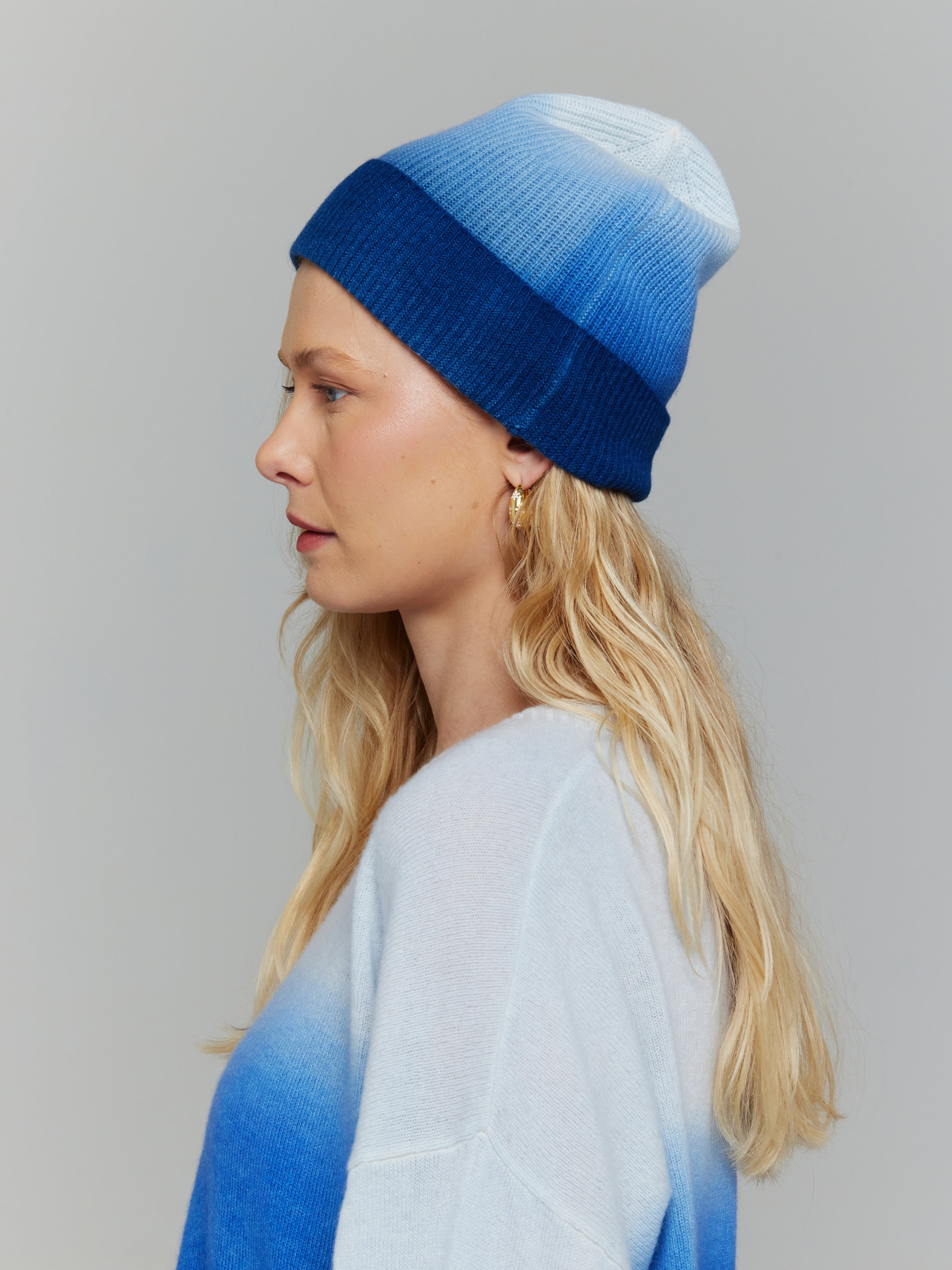 A person wearing a blue and white ombre beanie hat and matching jumper.