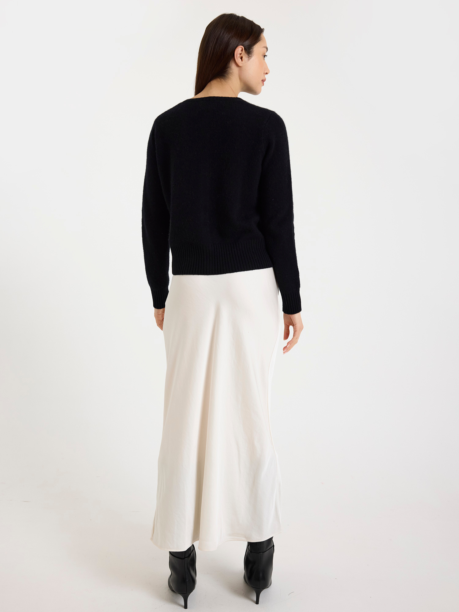 Woman wearing a black cardigan and white skirt on a white background