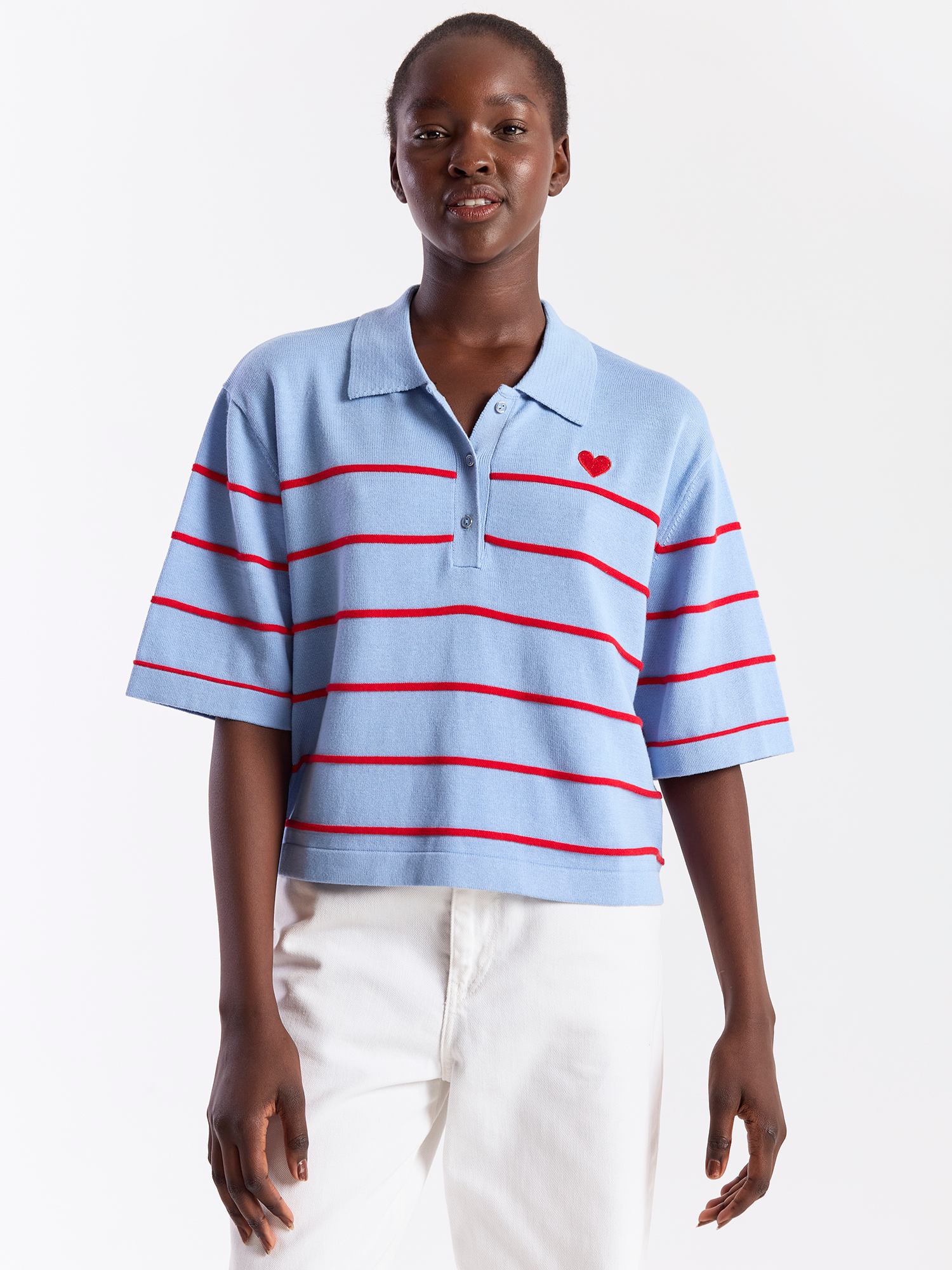 Person wearing a light blue polo shirt with red stripes and a red heart on a white background