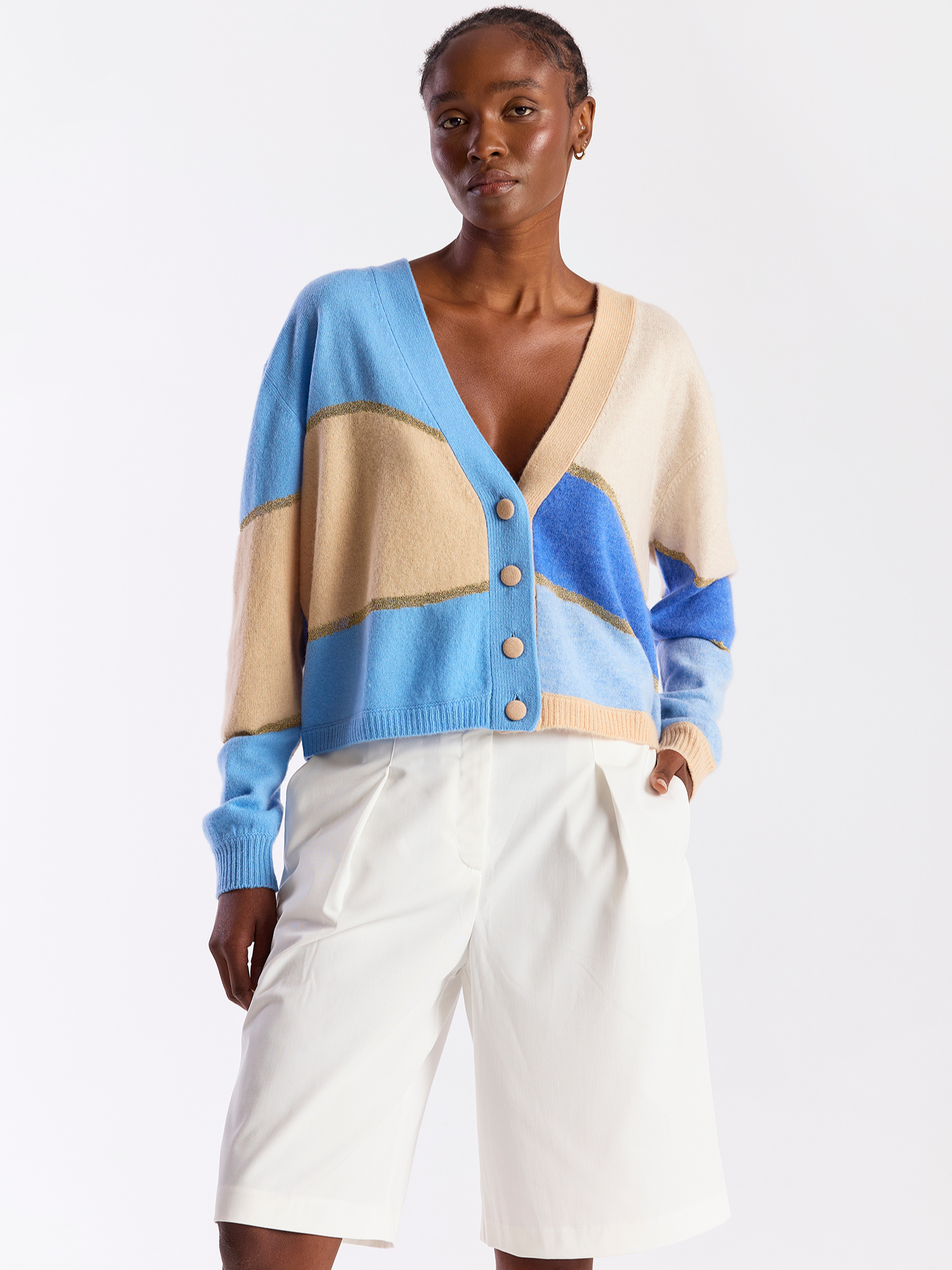 Woman wearing a blue and beige cashmere cardigan with button details on a white background