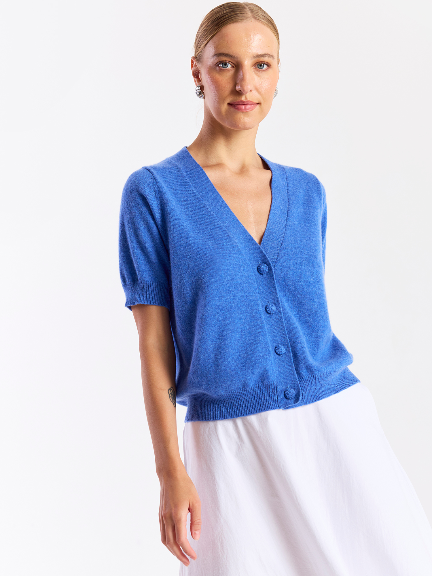 Woman wearing a blue cardigan over a white top on a white background