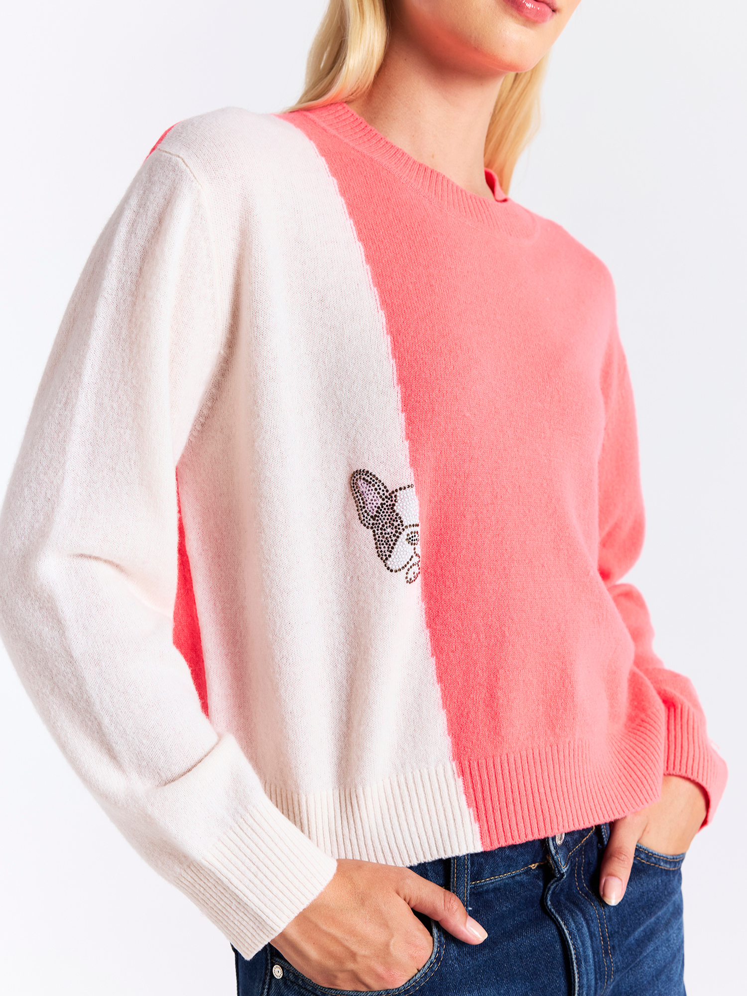 Person wearing a color-blocked sweater with white, pink, and blue sections on a plain background