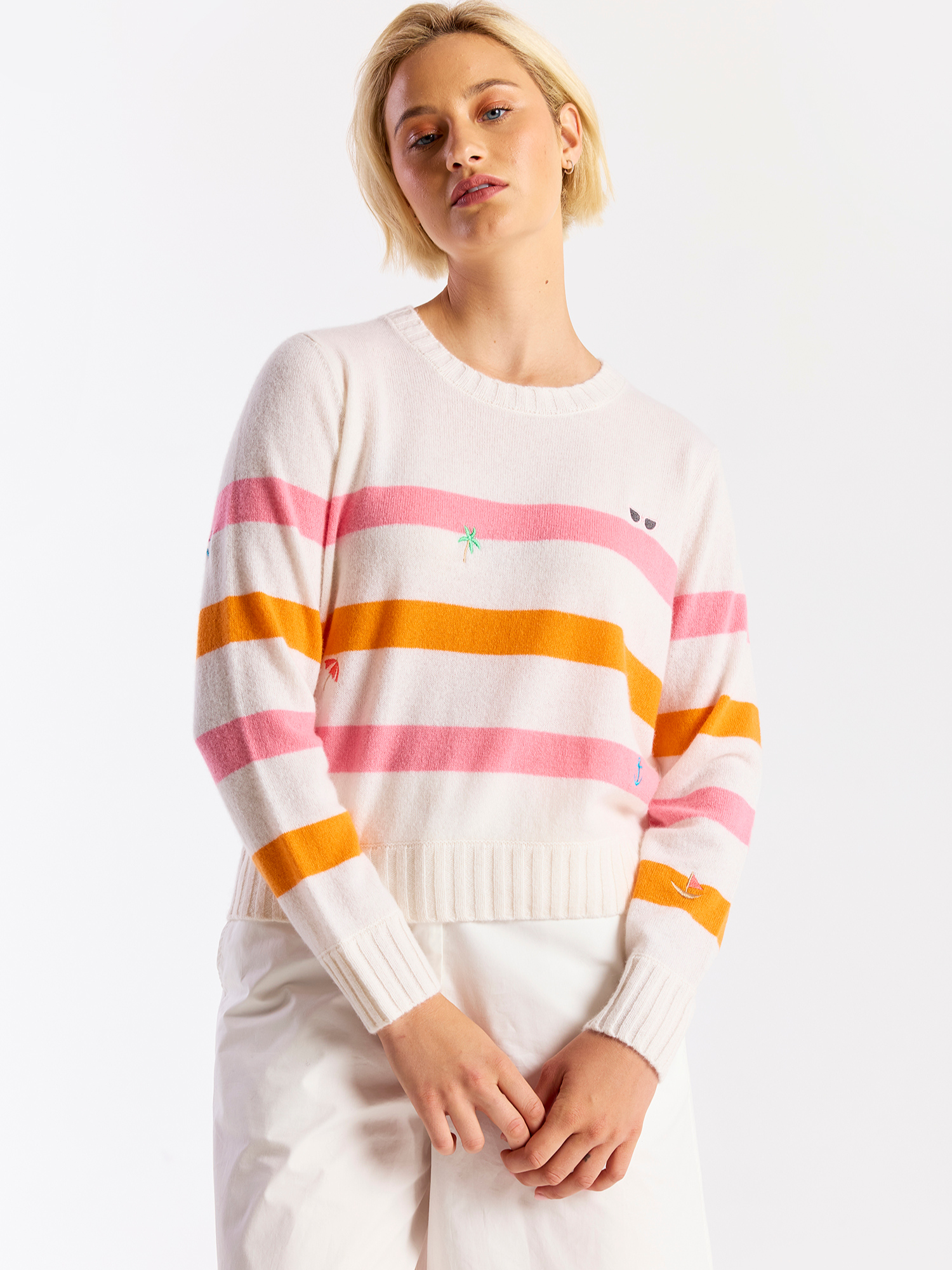 Woman wearing a striped cashmere sweater with pink and orange horizontal stripes on a white background
