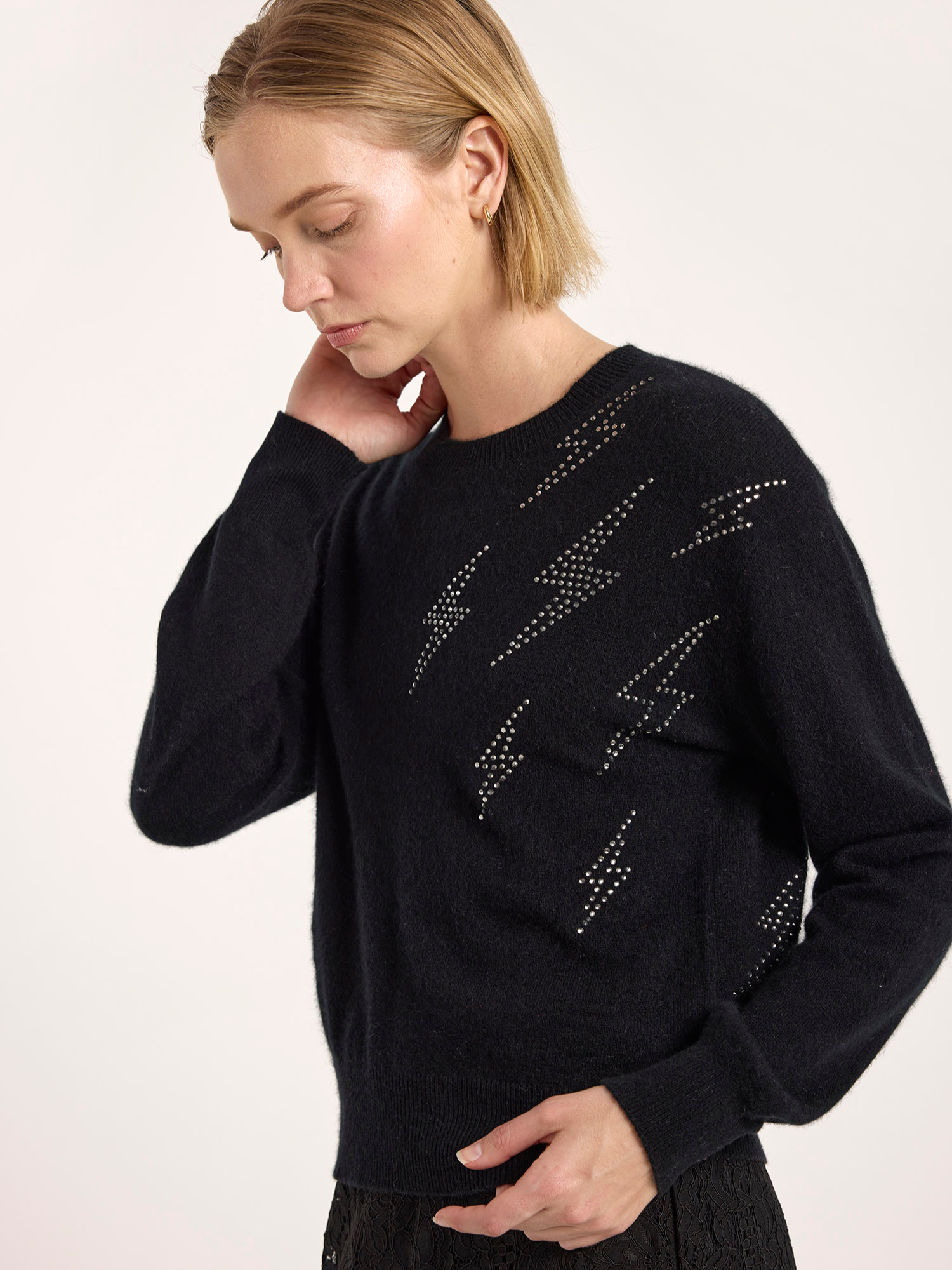 Woman wearing a black sweater with star patterns on a light background