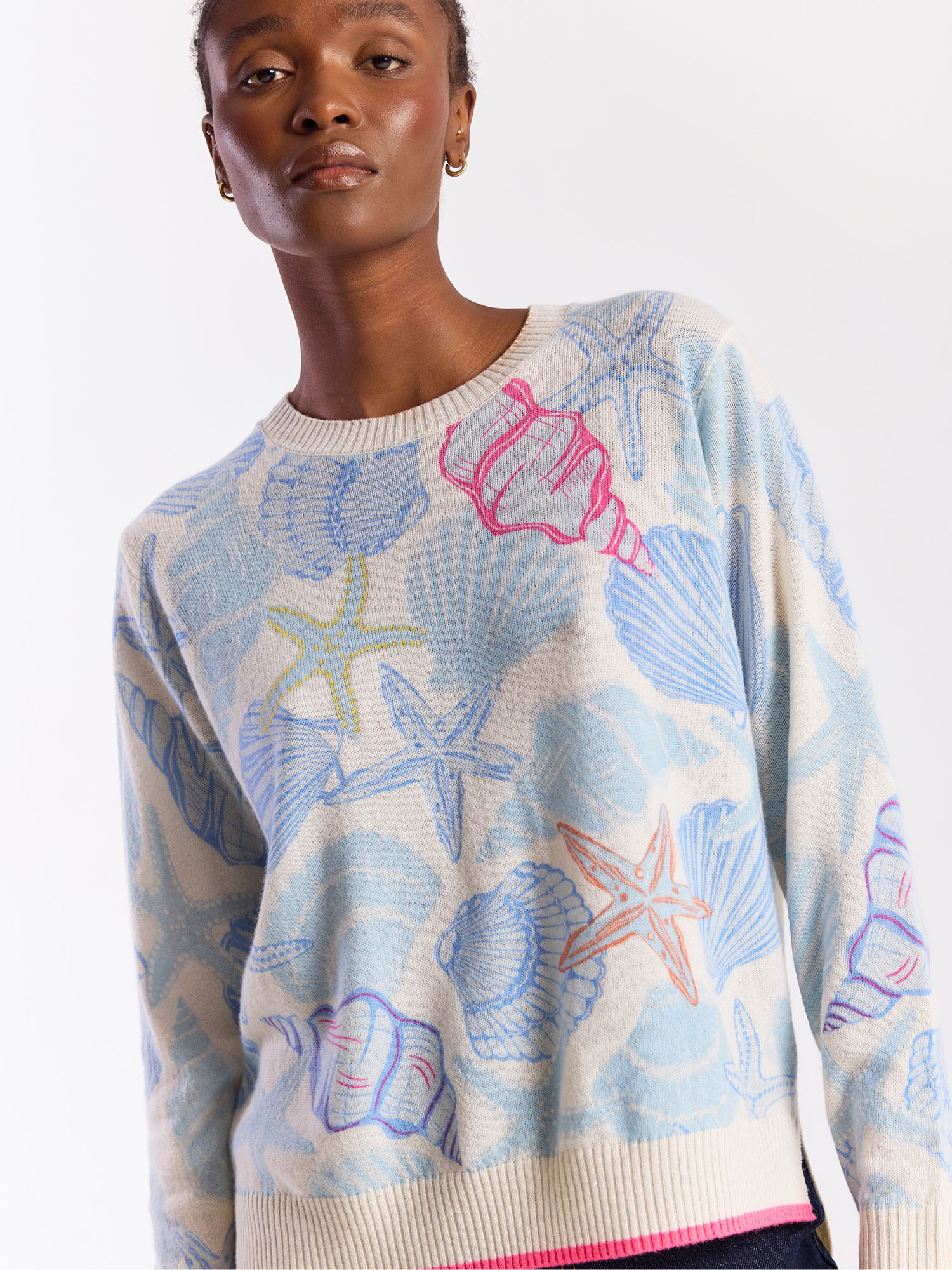 Person wearing a sweater with beach-themed patterns on a white background