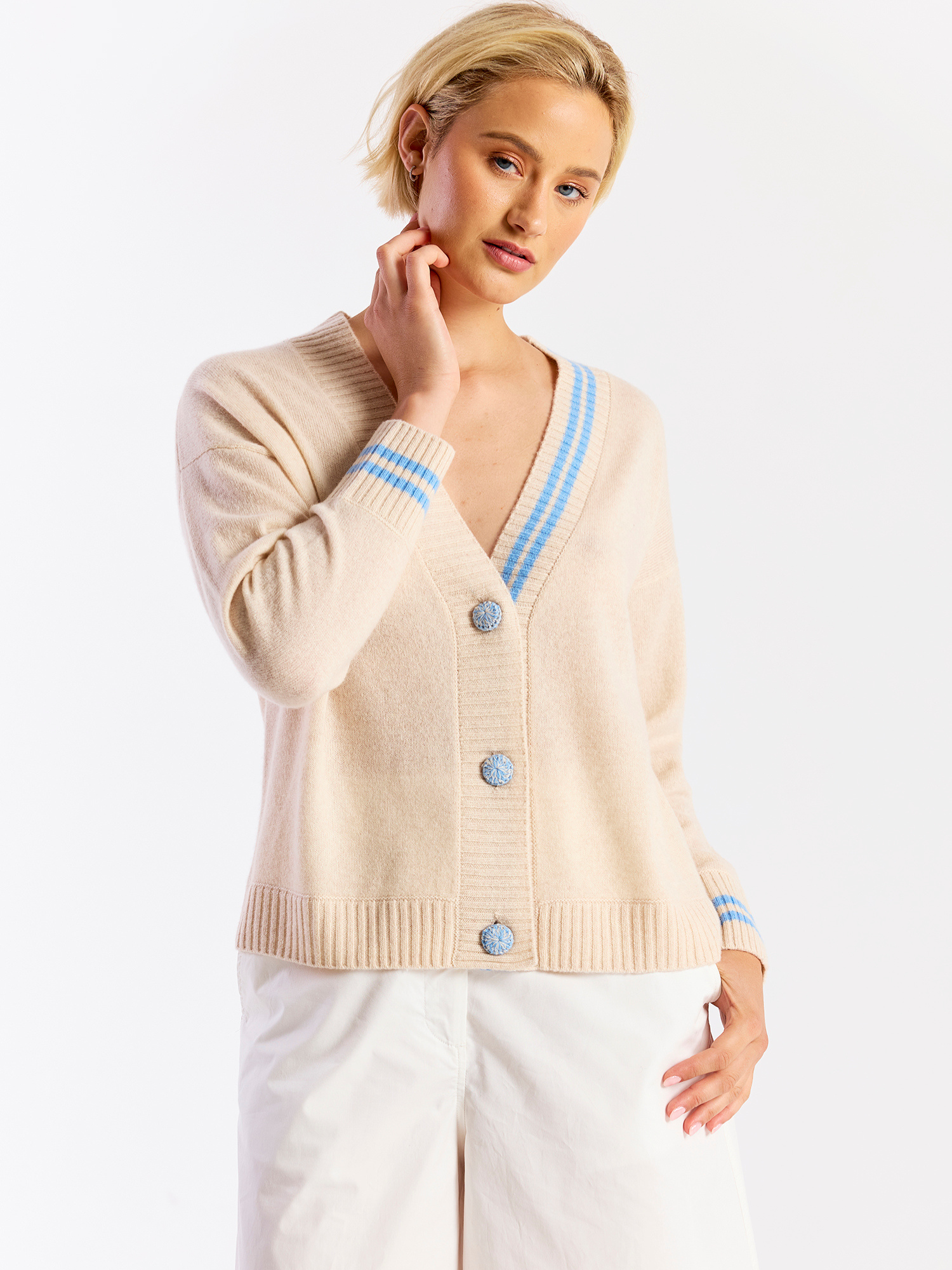 Woman wearing a beige cardigan with blue accents on a white background