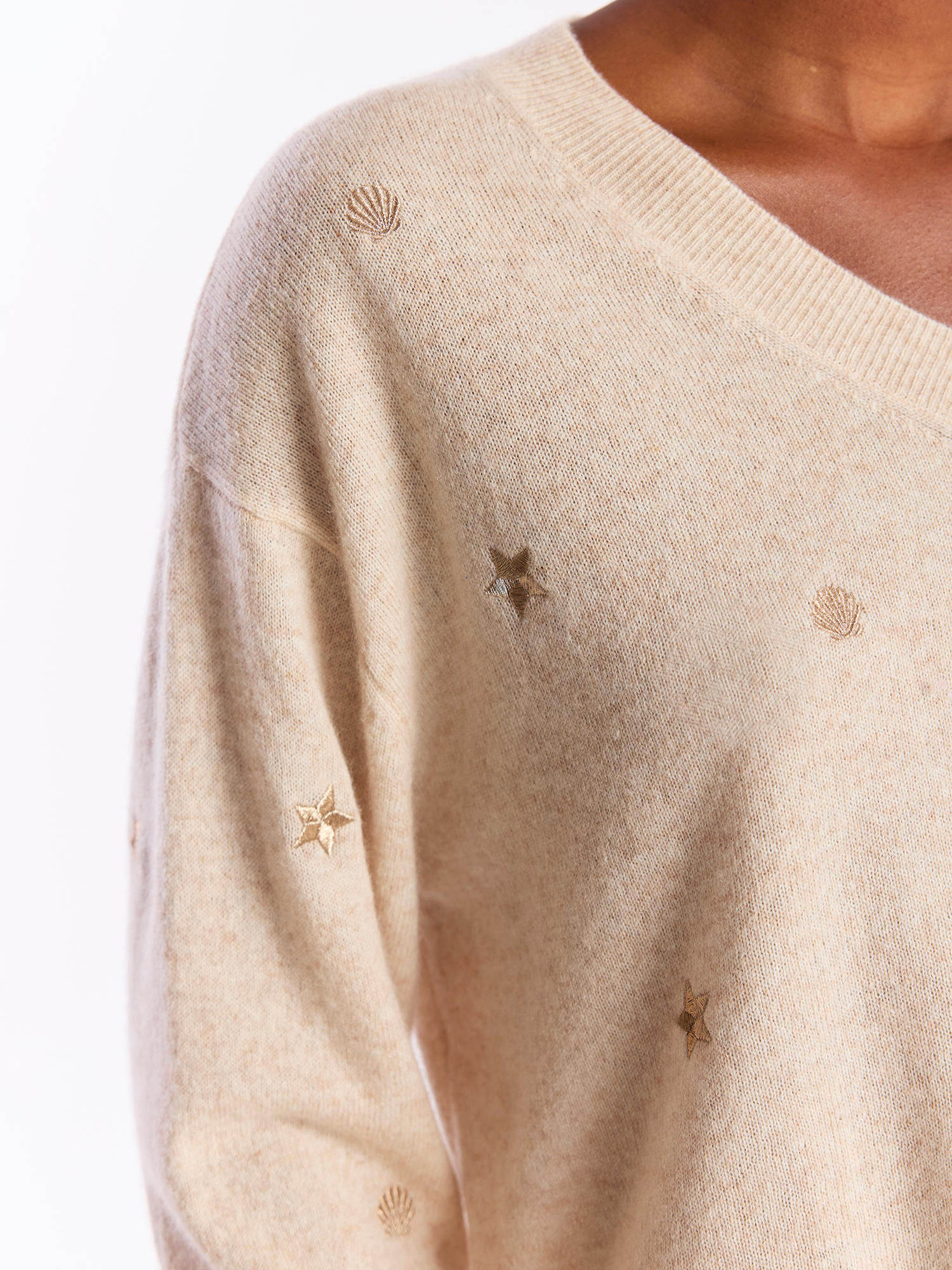 Beige sweater with star and shell patterns on a white background