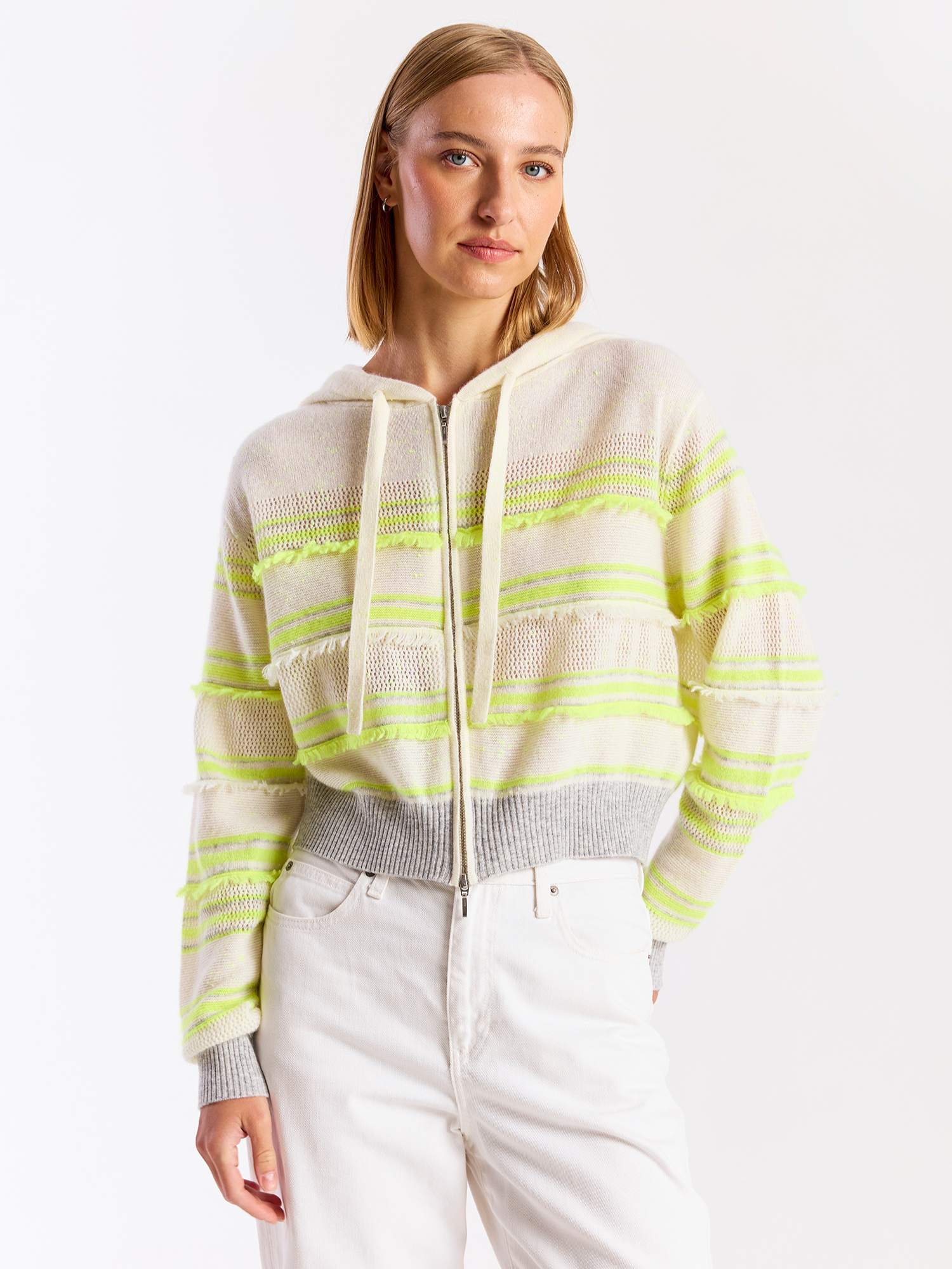 Woman wearing a light-colored sweater with green stripes on a white background