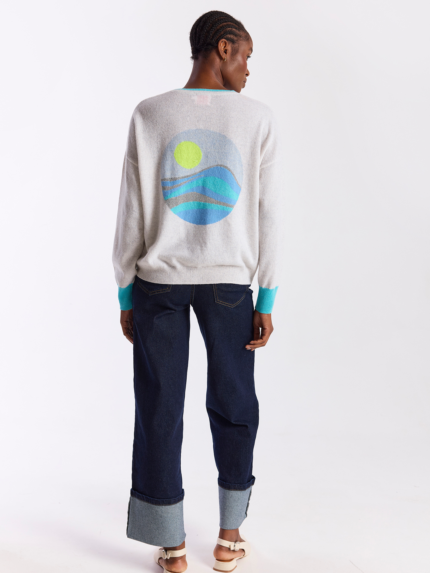 Person wearing a gray sweatshirt with a colorful graphic on the back, standing against a white background.