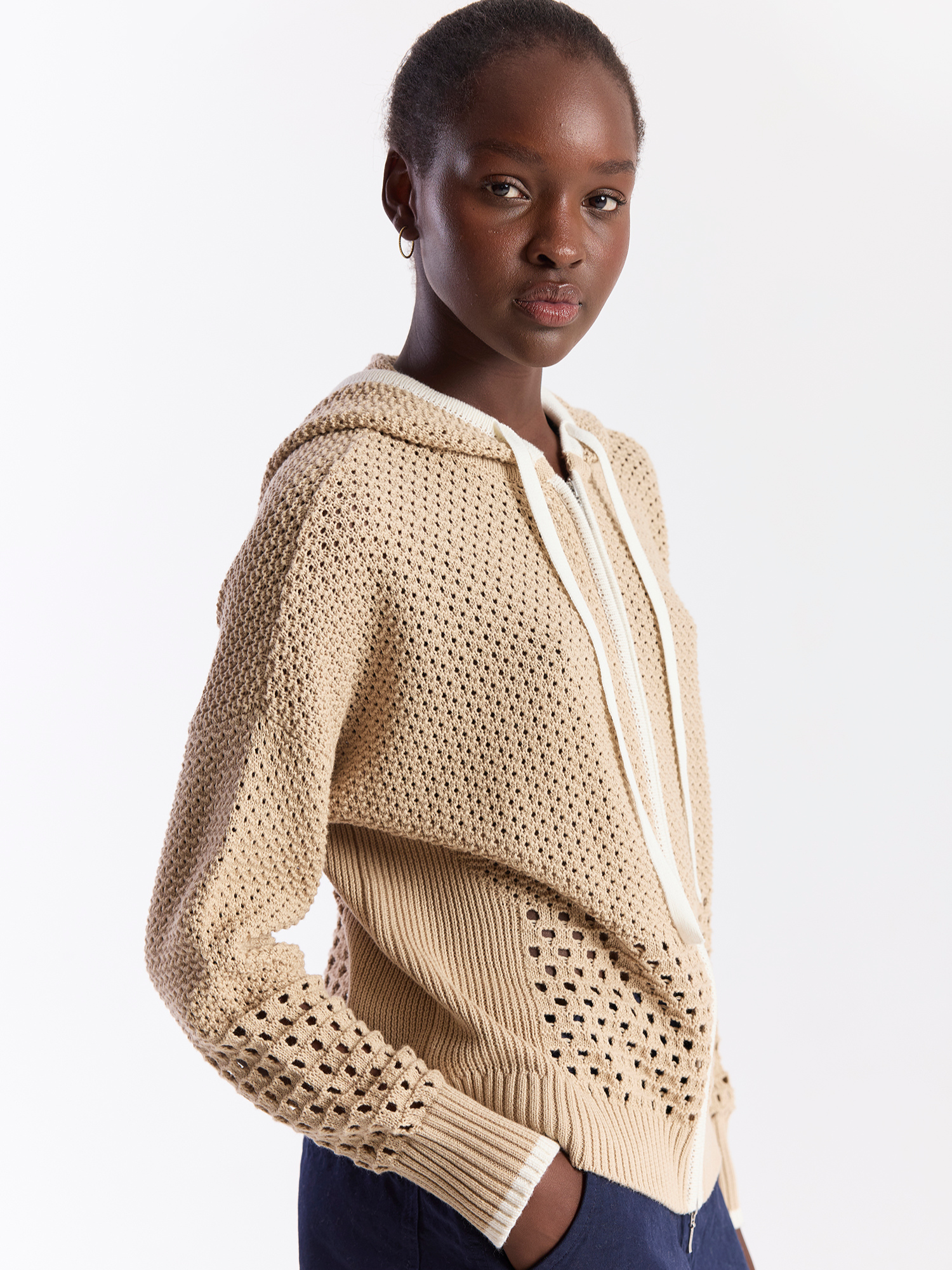 Woman wearing a beige knitted hoodie on a white background