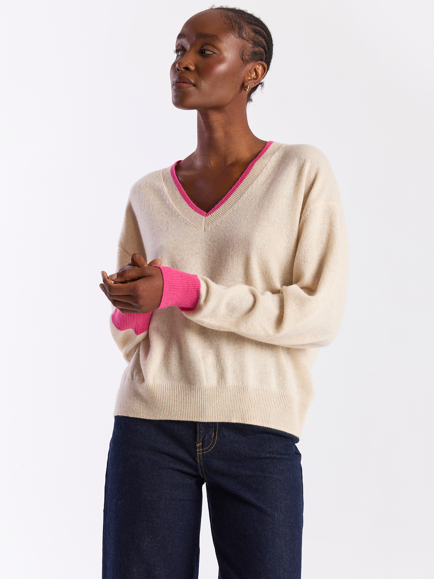 Woman wearing a beige sweater with pink trim on a white background