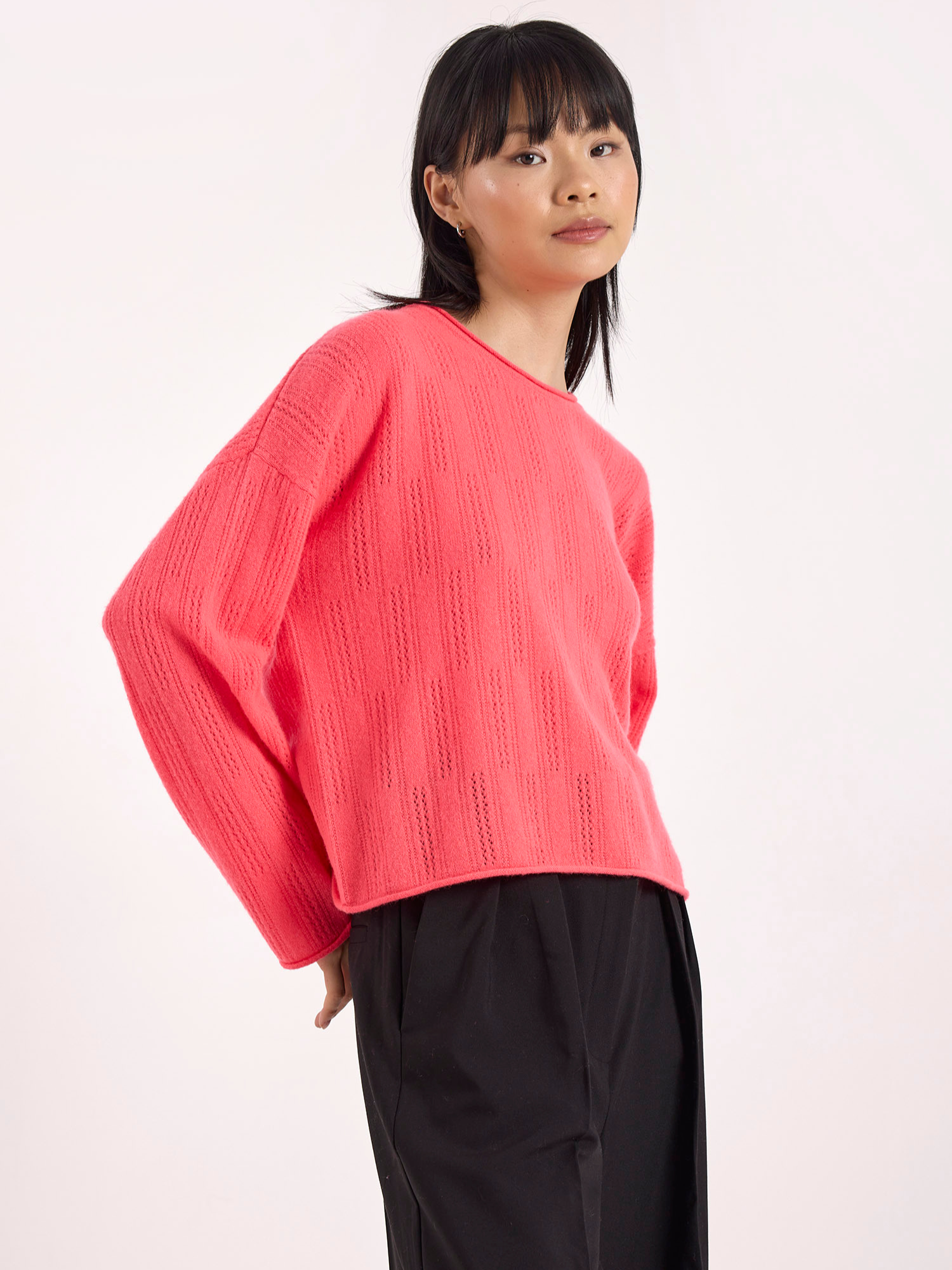 Person wearing a pink sweater and black pants on a white background