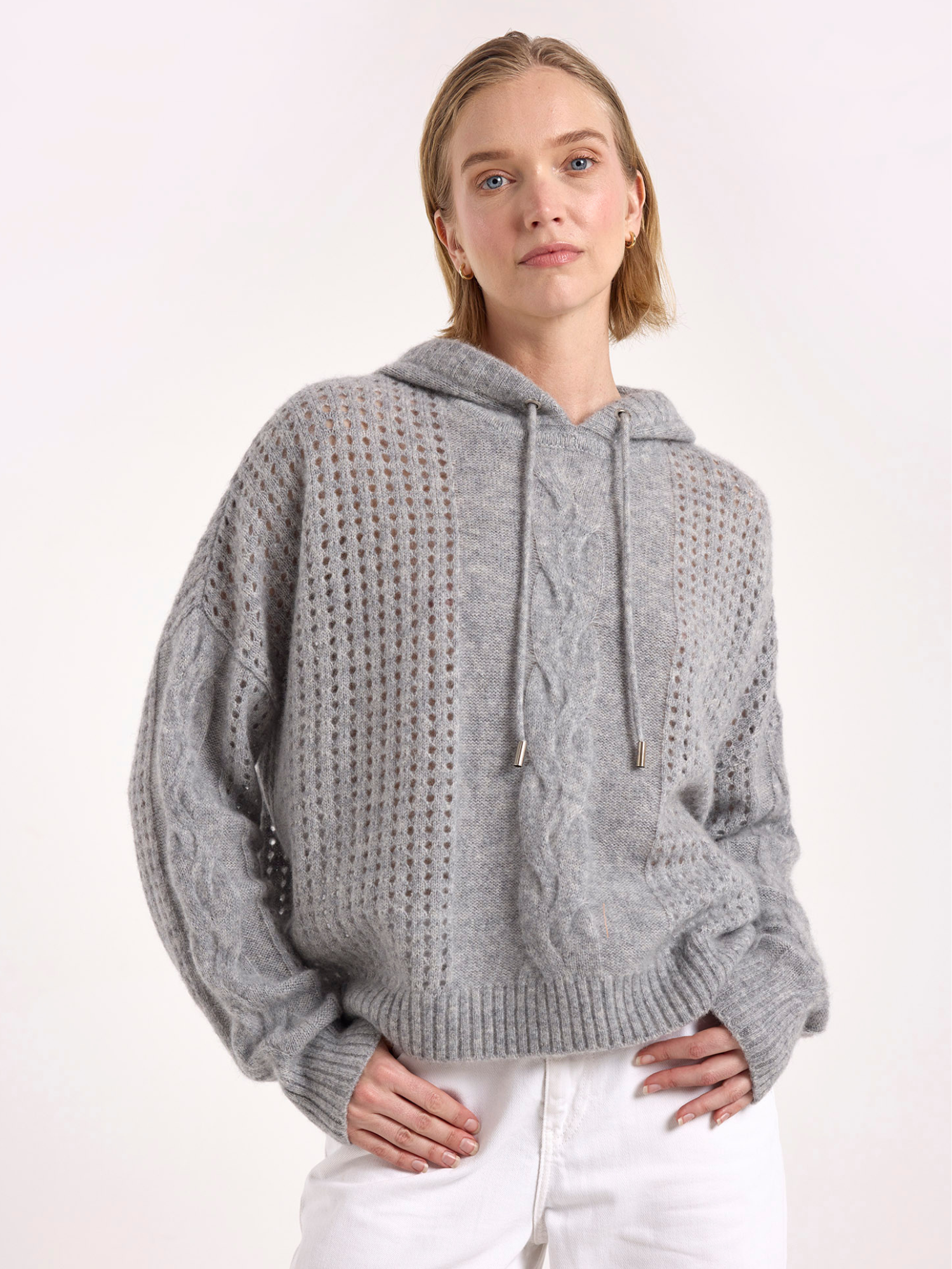 Woman wearing a grey knitted cashmere hoodie on a white background