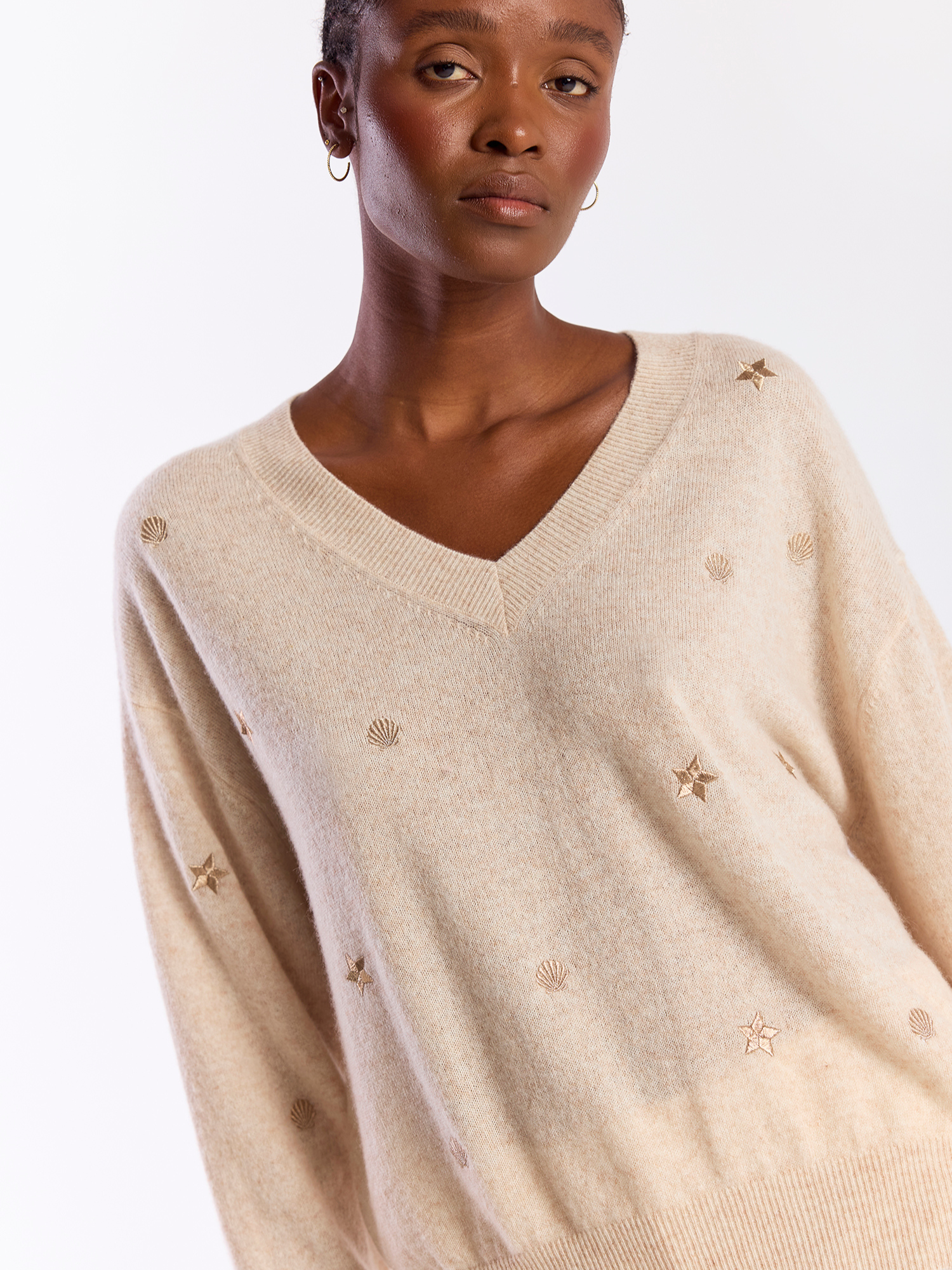 Woman wearing a beige sweater with star patterns on a white background