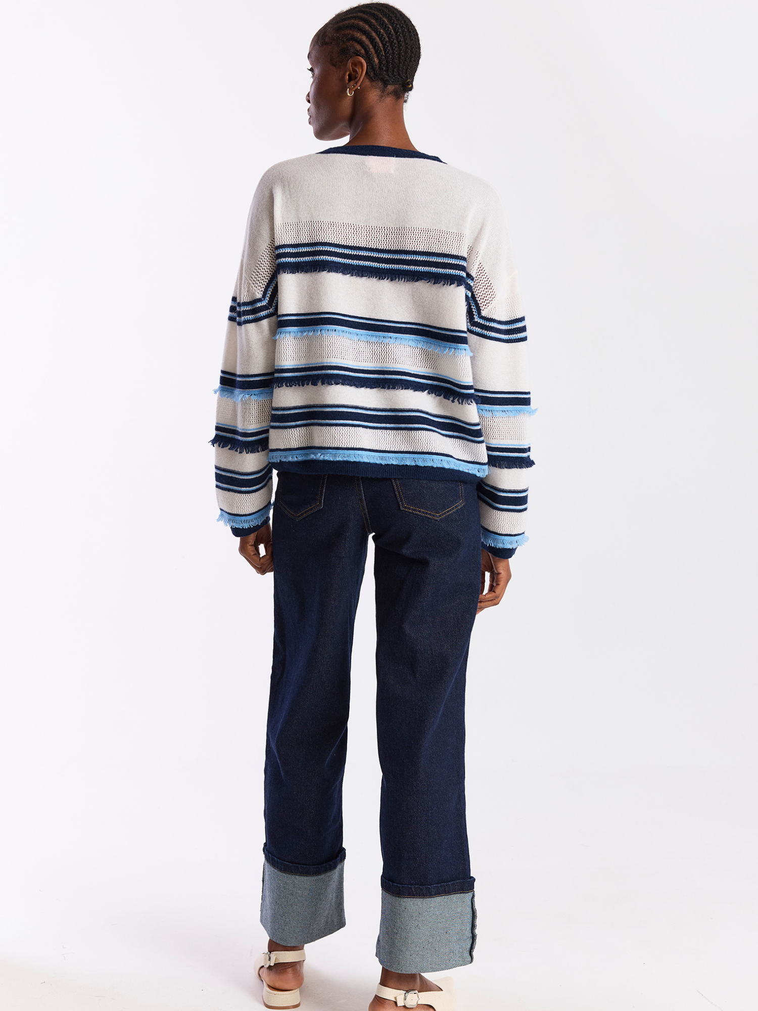 Person wearing a striped sweater and dark jeans on a white background