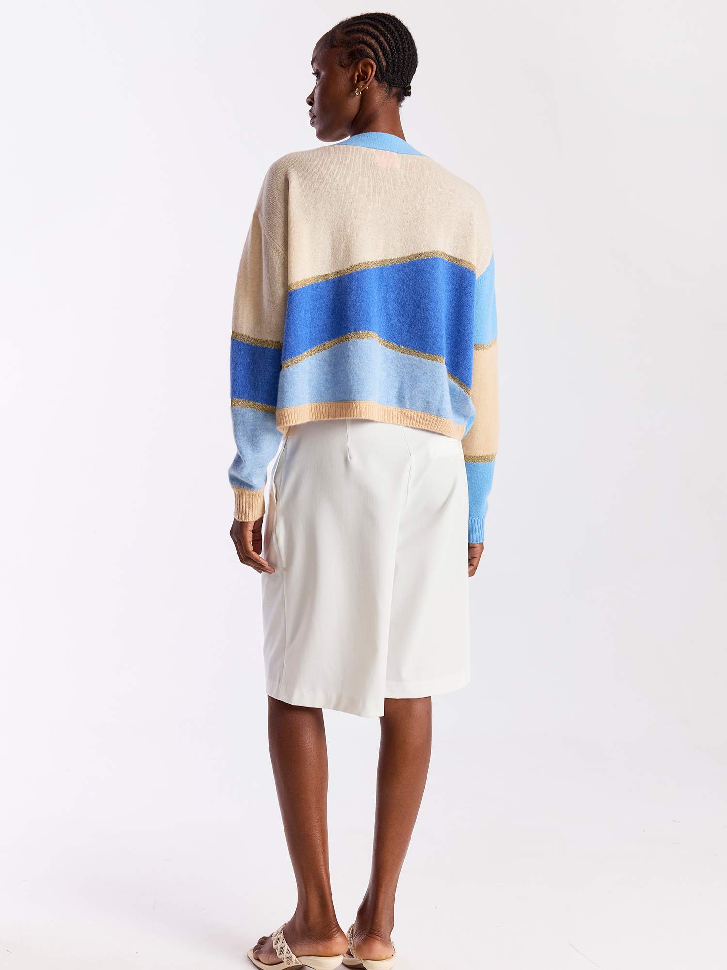 Woman wearing a blue and beige cashmere cardigan with button details on a white background