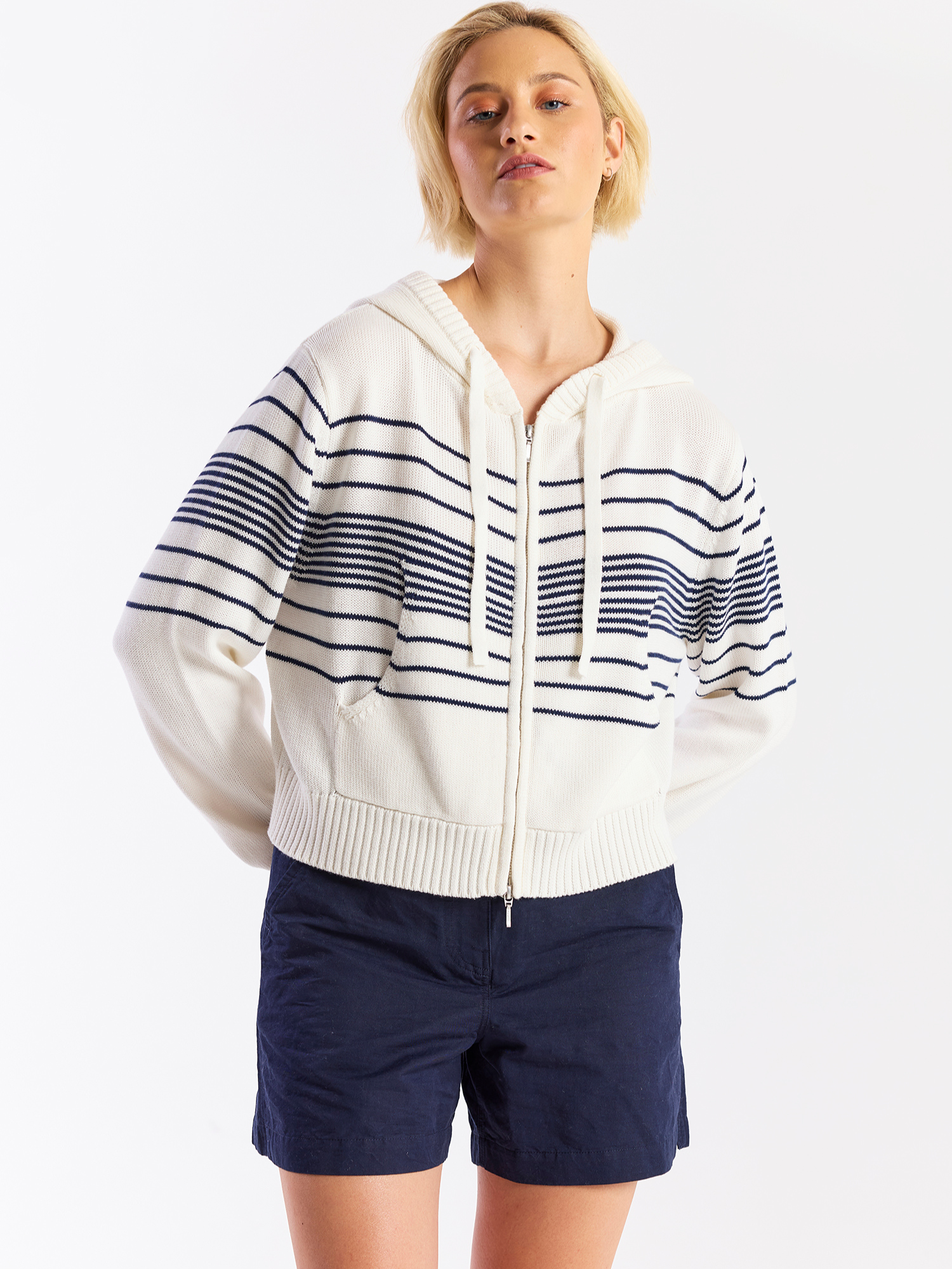 Woman wearing a striped hoodie and navy shorts on a white background