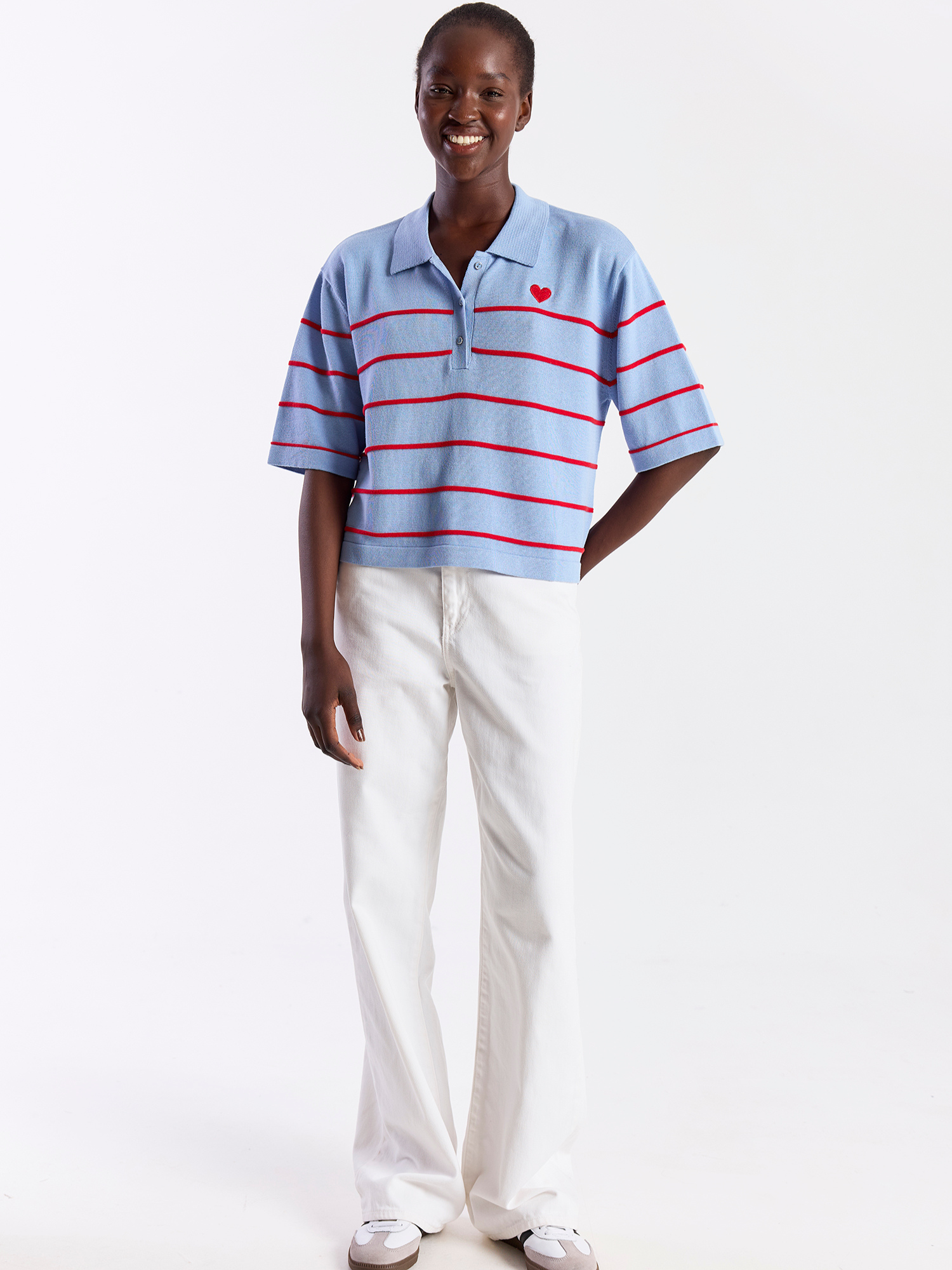 Person wearing a striped polo shirt and white pants on a white background