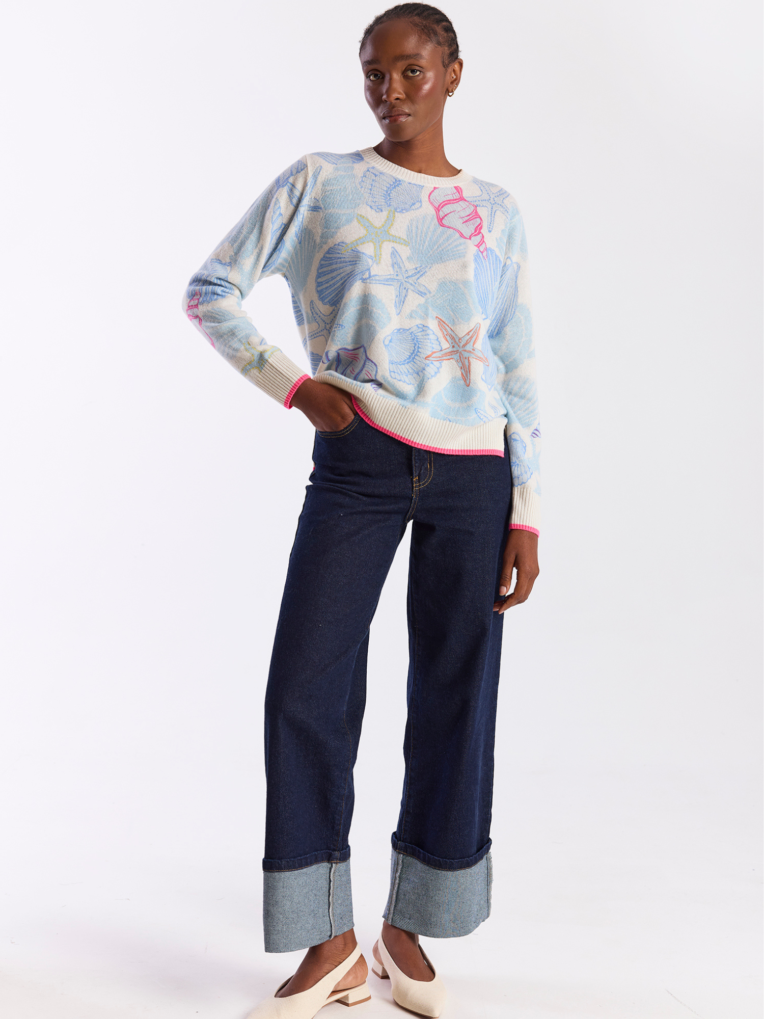 Person wearing a patterned sweater and navy pants on a white background