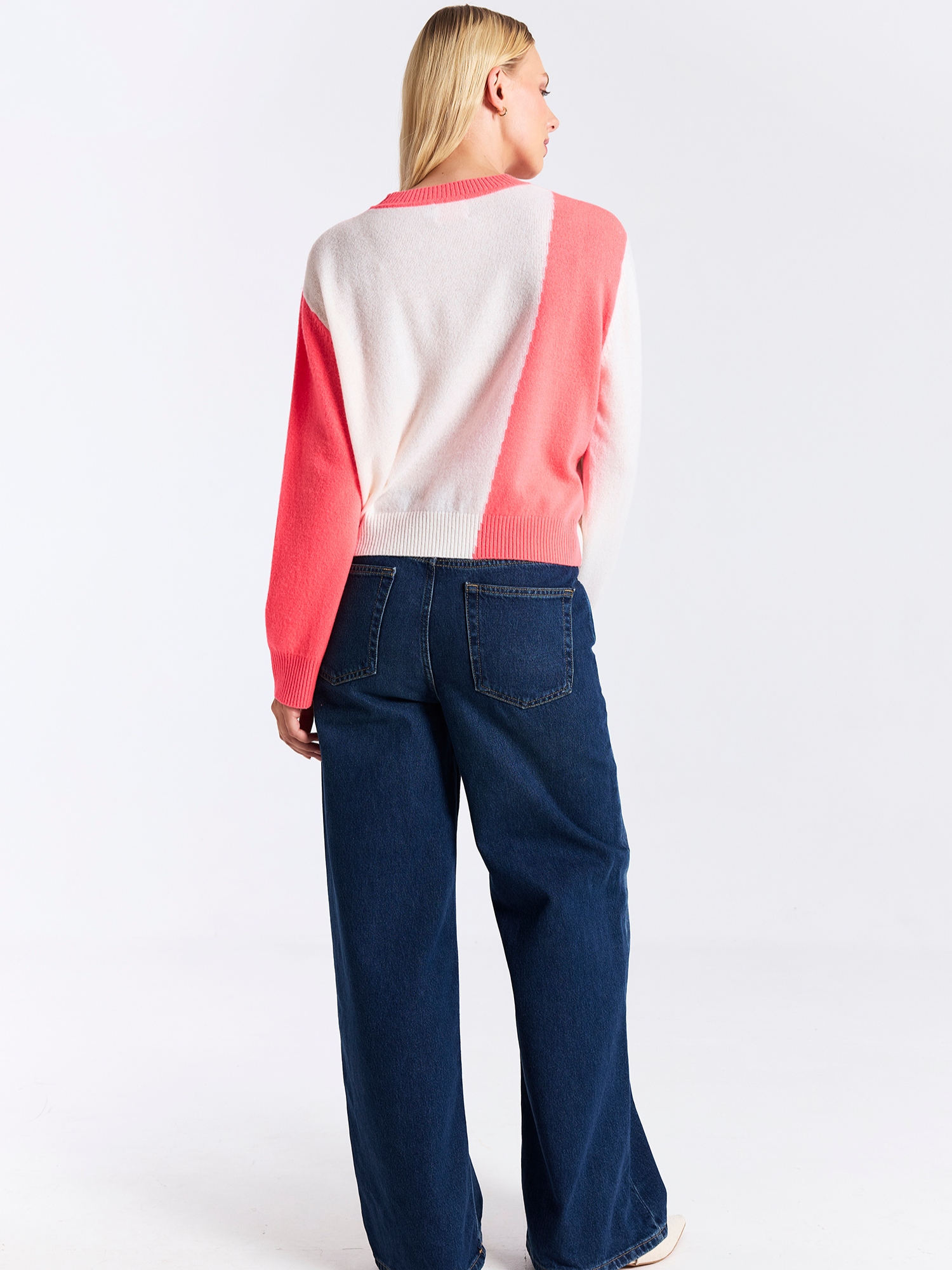 Person wearing a colorful sweater and blue jeans on a white background