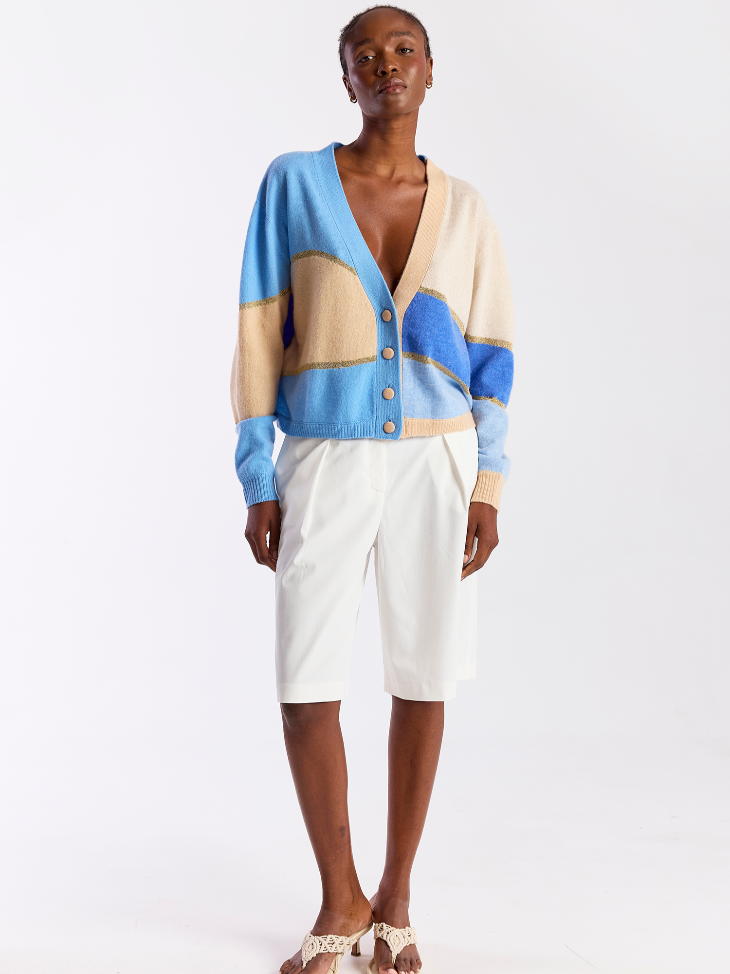 Woman wearing a blue and beige cashmere cardigan with button details on a white background