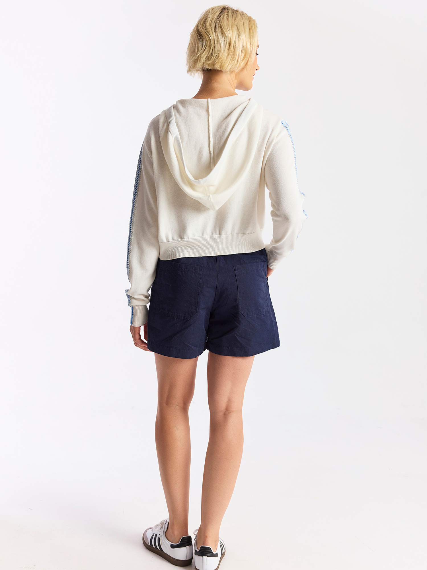 Person wearing a white hoodie and navy shorts on a white background