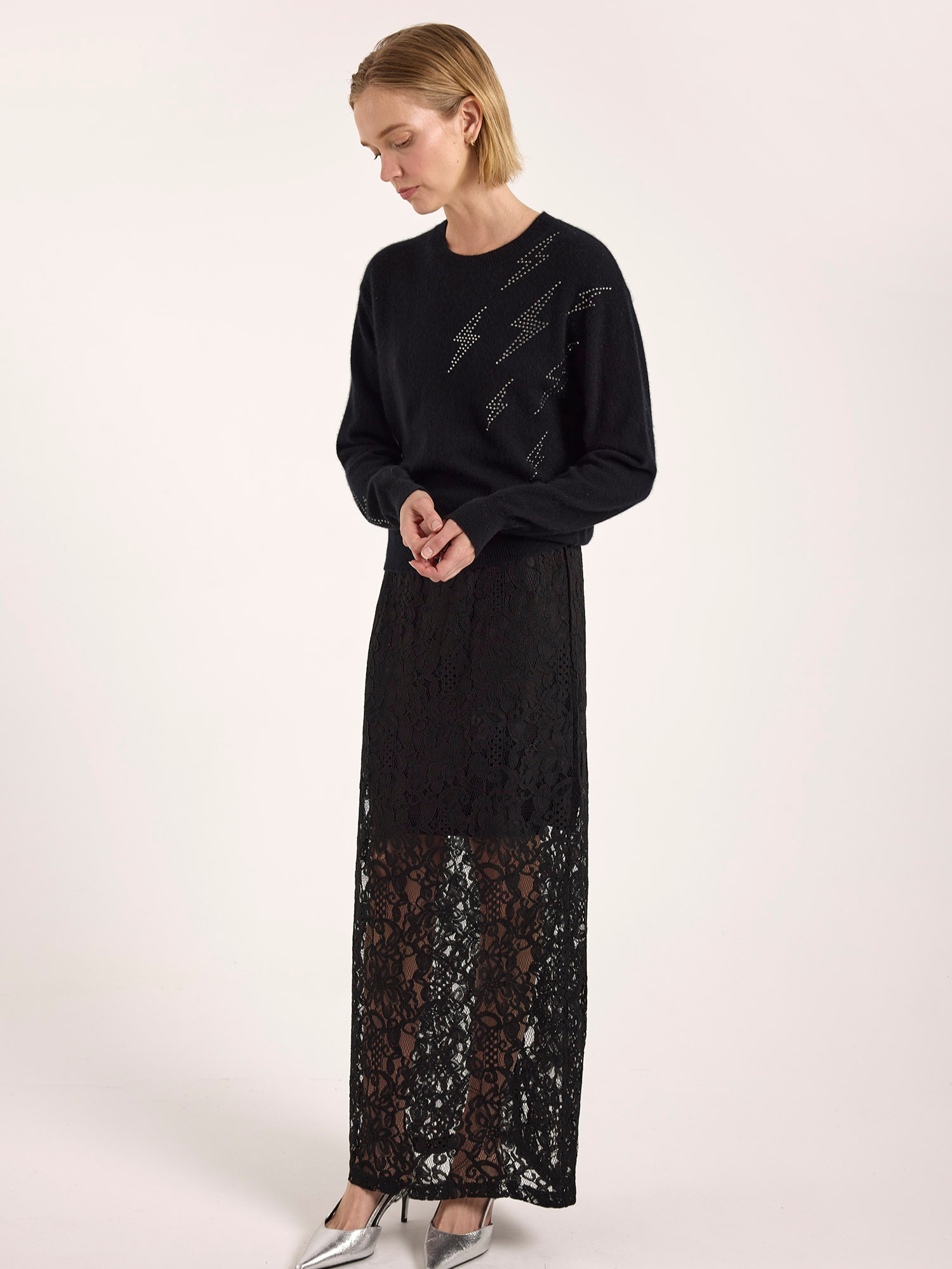 Woman wearing a black dress with lace detailing on a white background