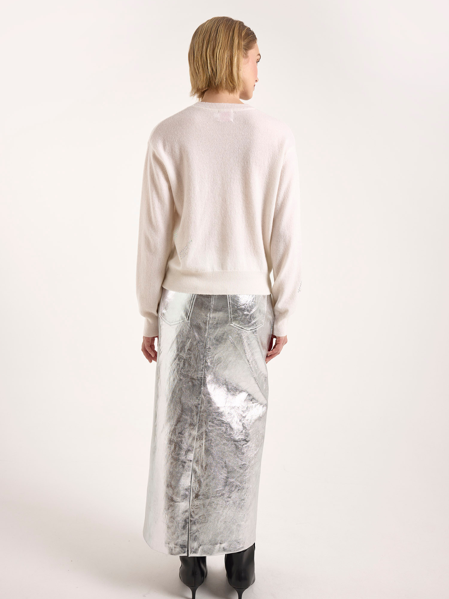 Woman wearing a long, light-colored skirt with a subtle pattern on a white background