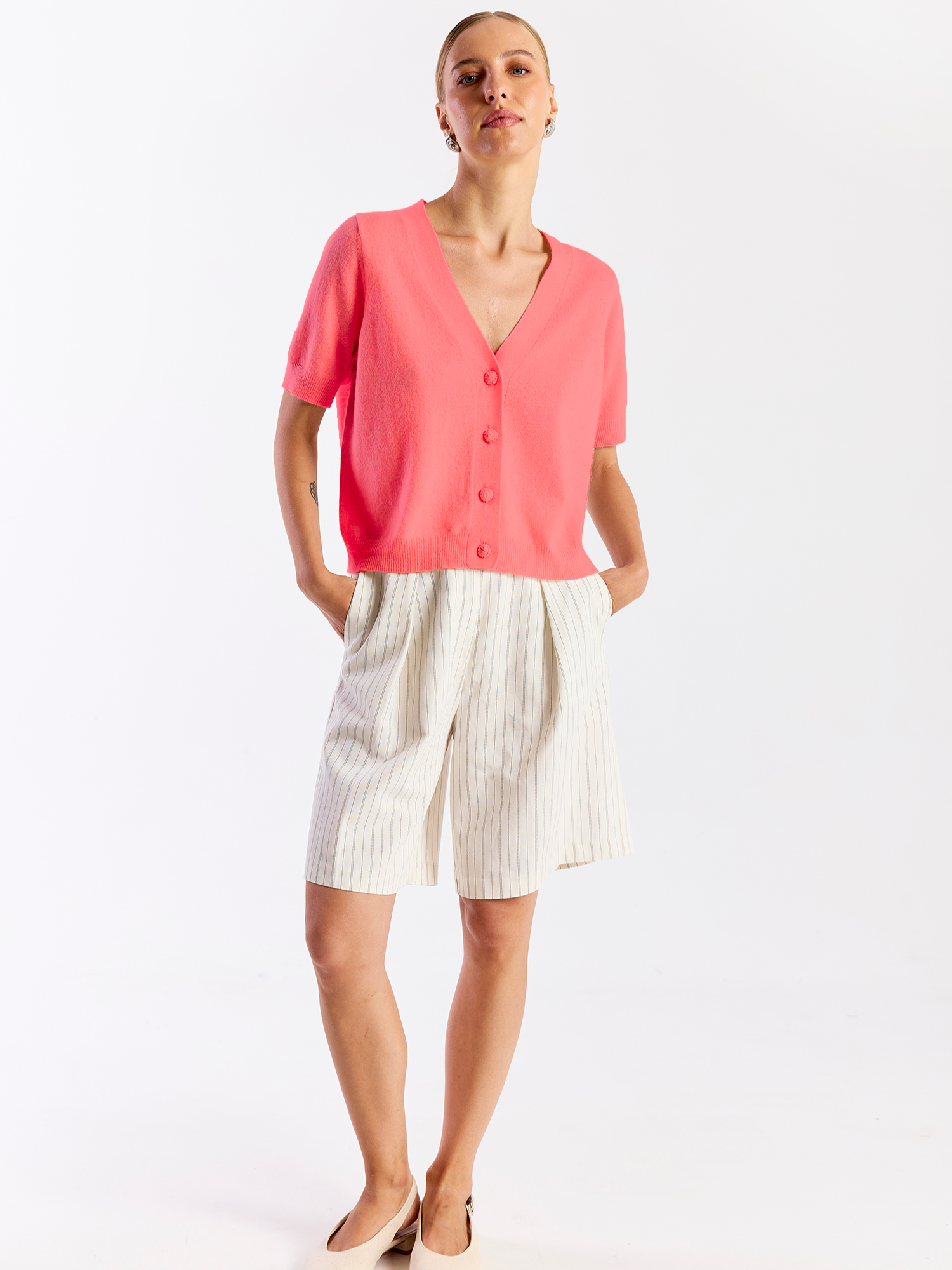 Woman wearing a coral blouse and white skirt on a white background