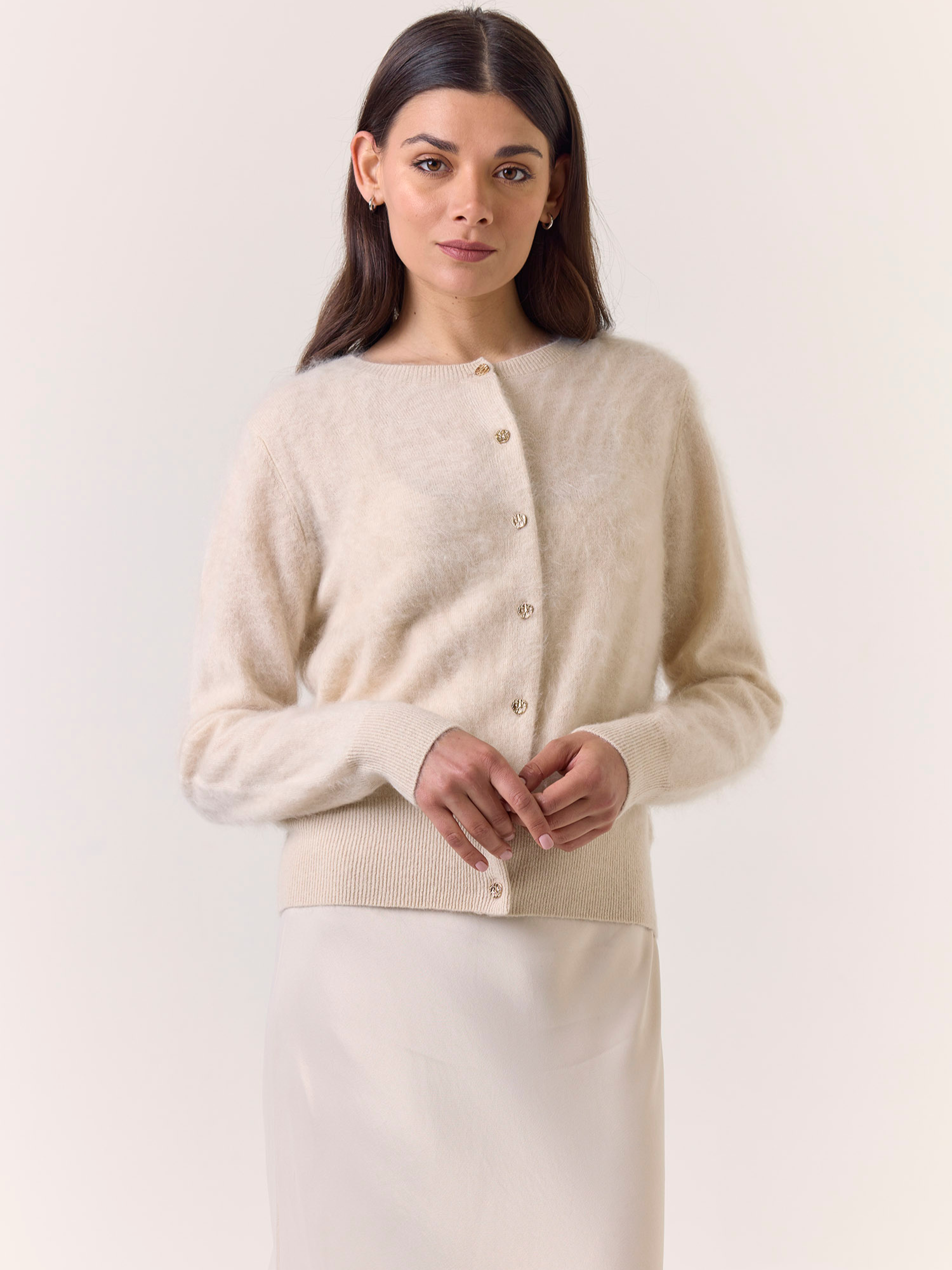 Woman wearing a beige cardigan against a white background