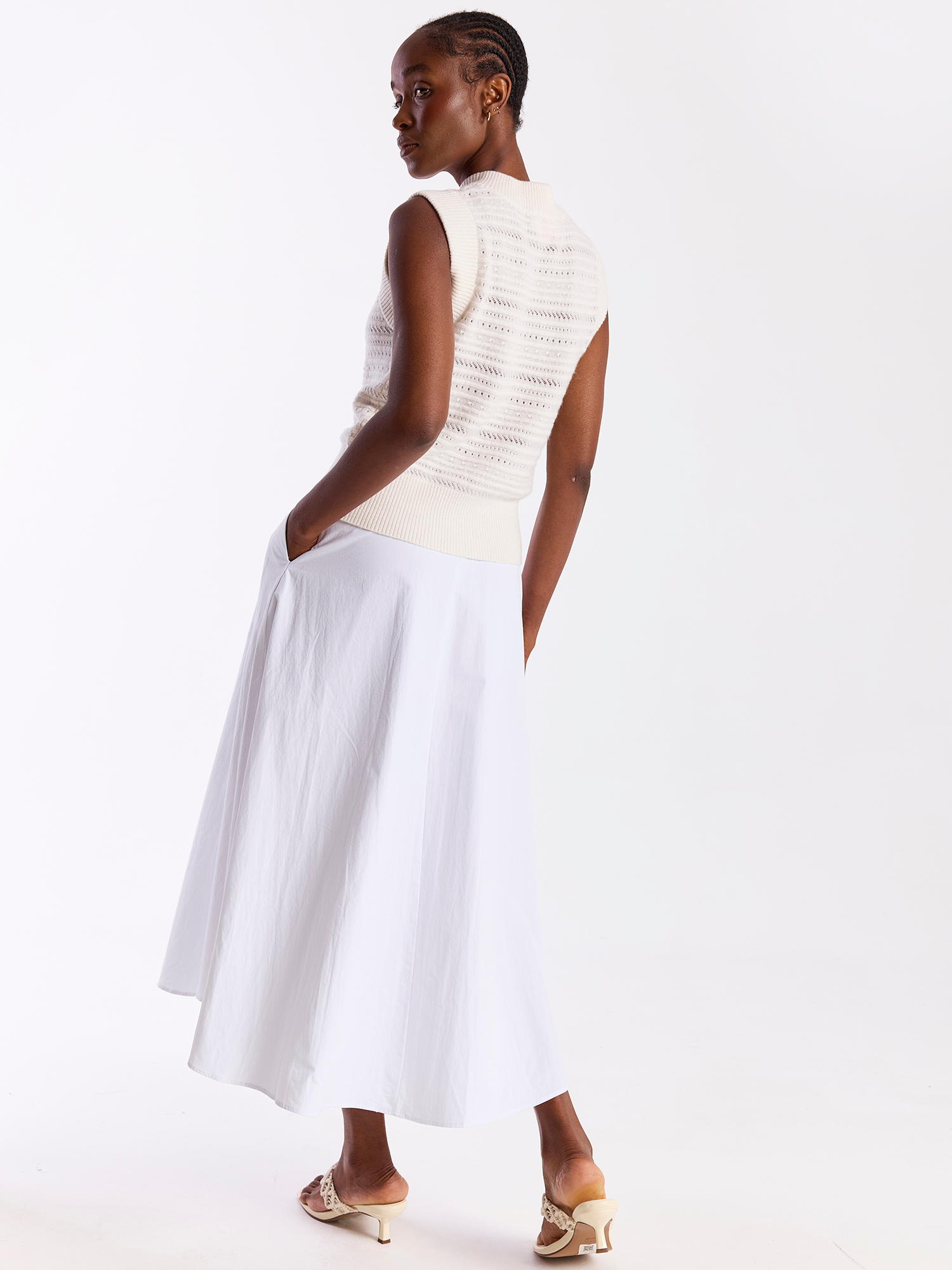 Woman wearing a white sleeveless top and skirt on a white background