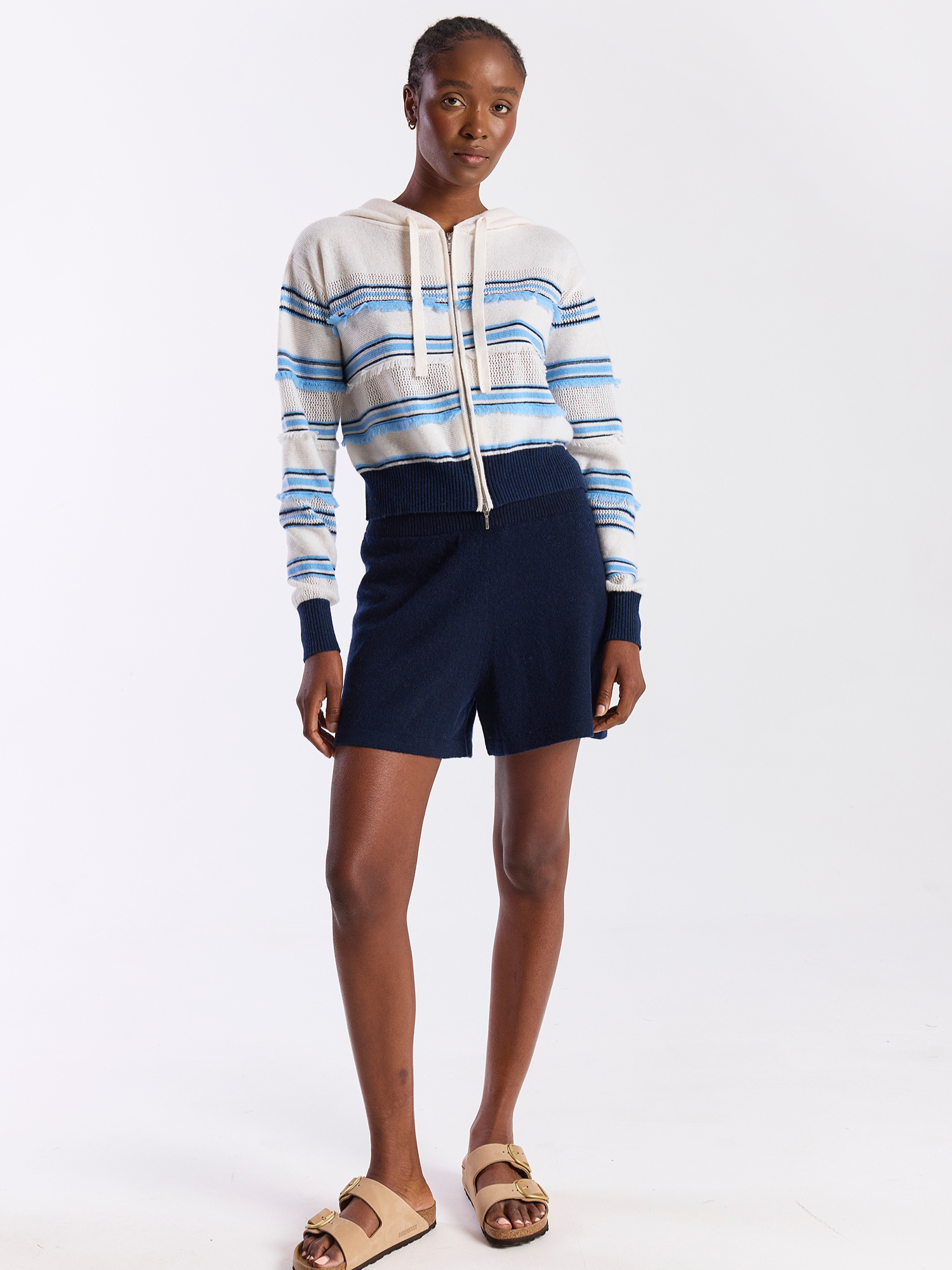 Woman wearing a striped hoodie and navy shorts on a white background