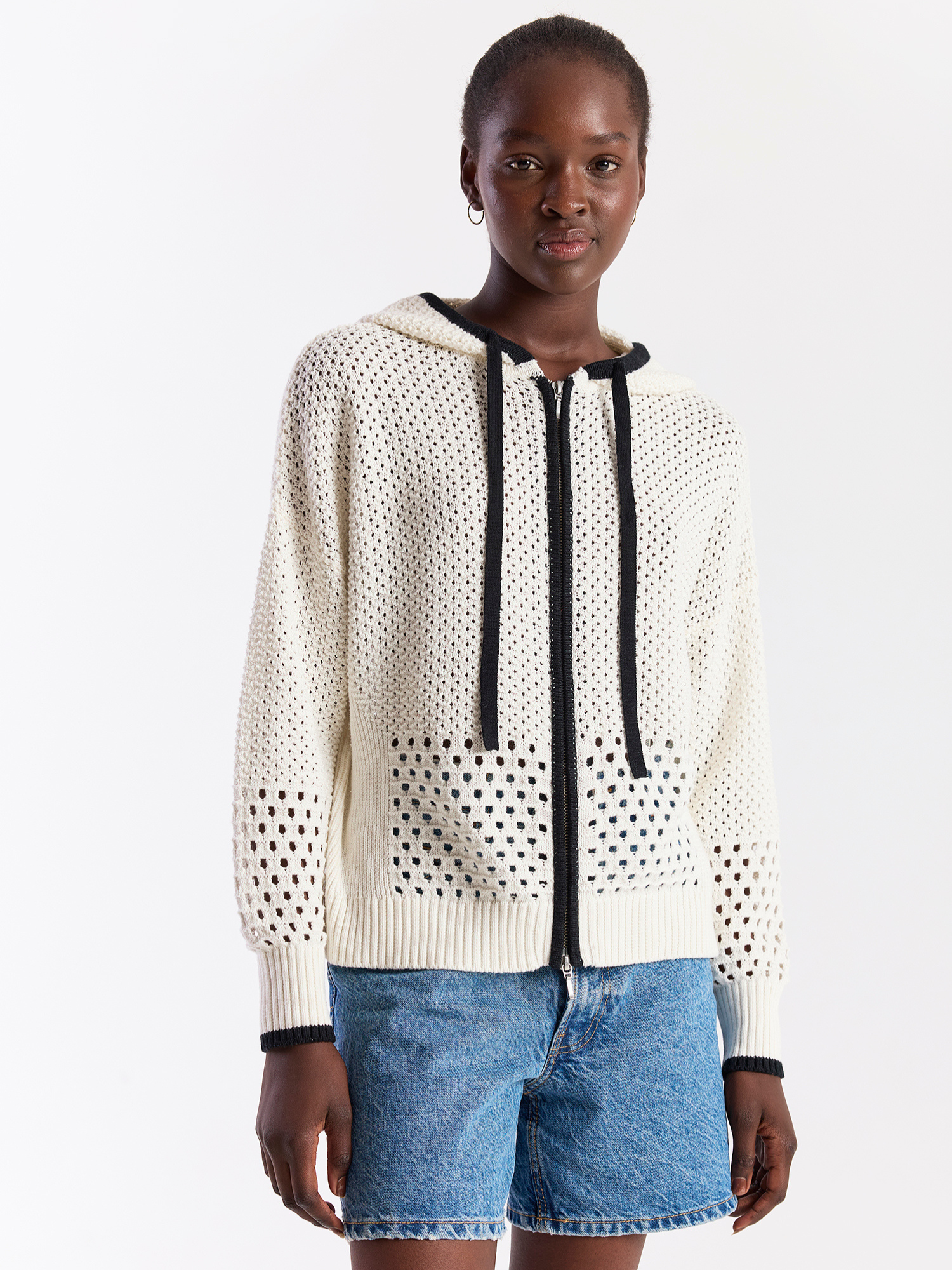 Person wearing a white perforated hoodie with black accents on a white background