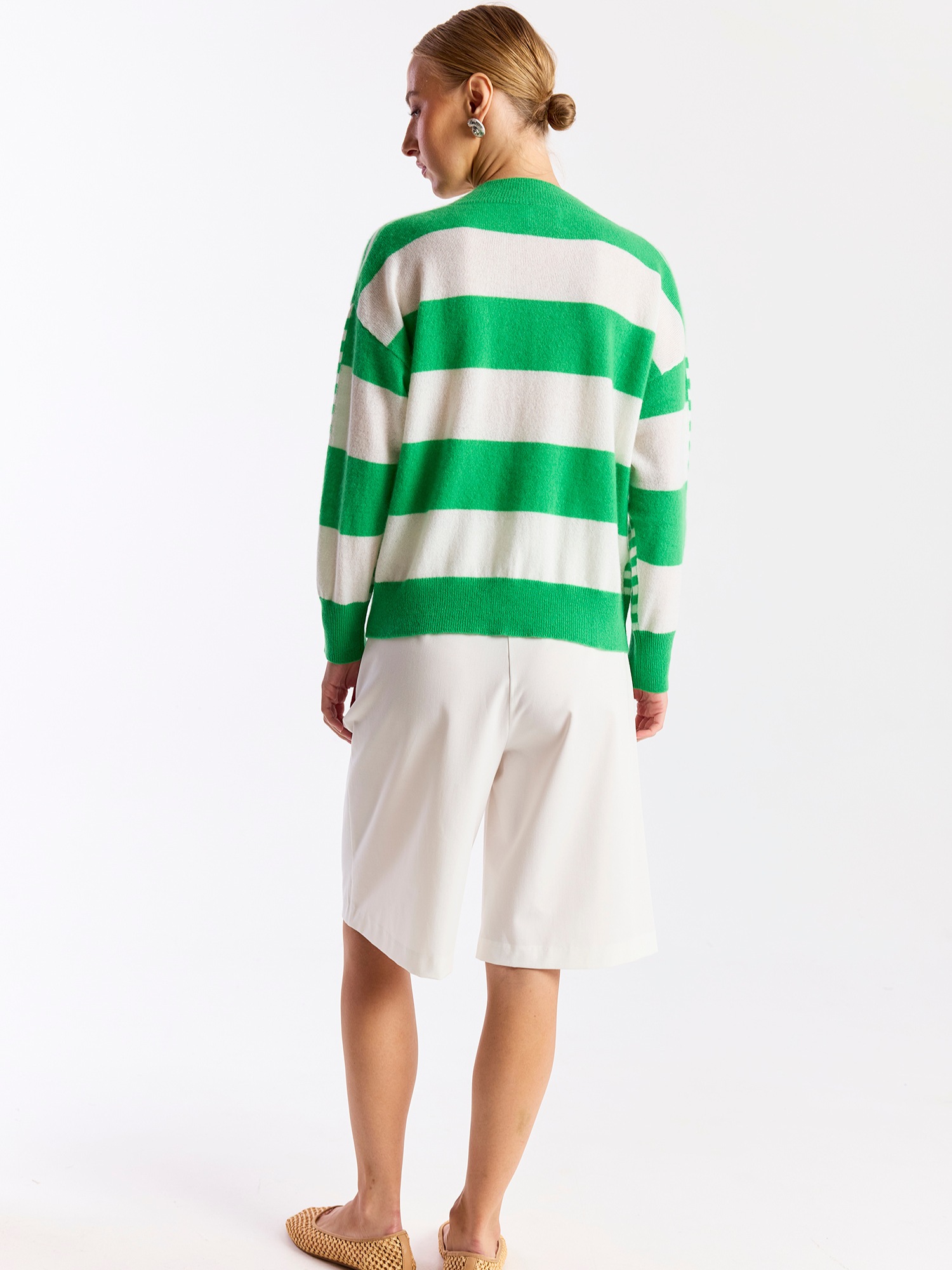 Person wearing a green and white striped sweater with a white skirt on a white background
