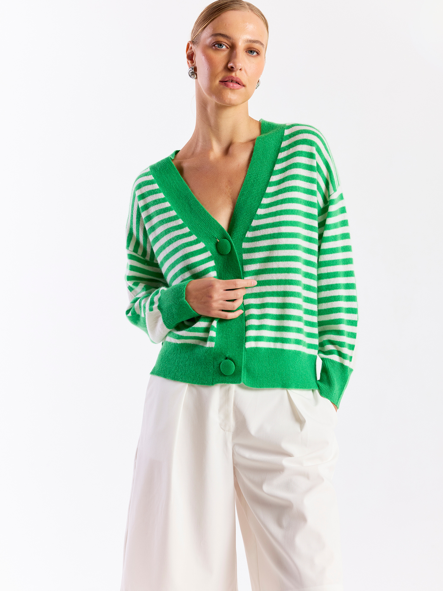 Woman wearing a green and white striped cardigan on a white background