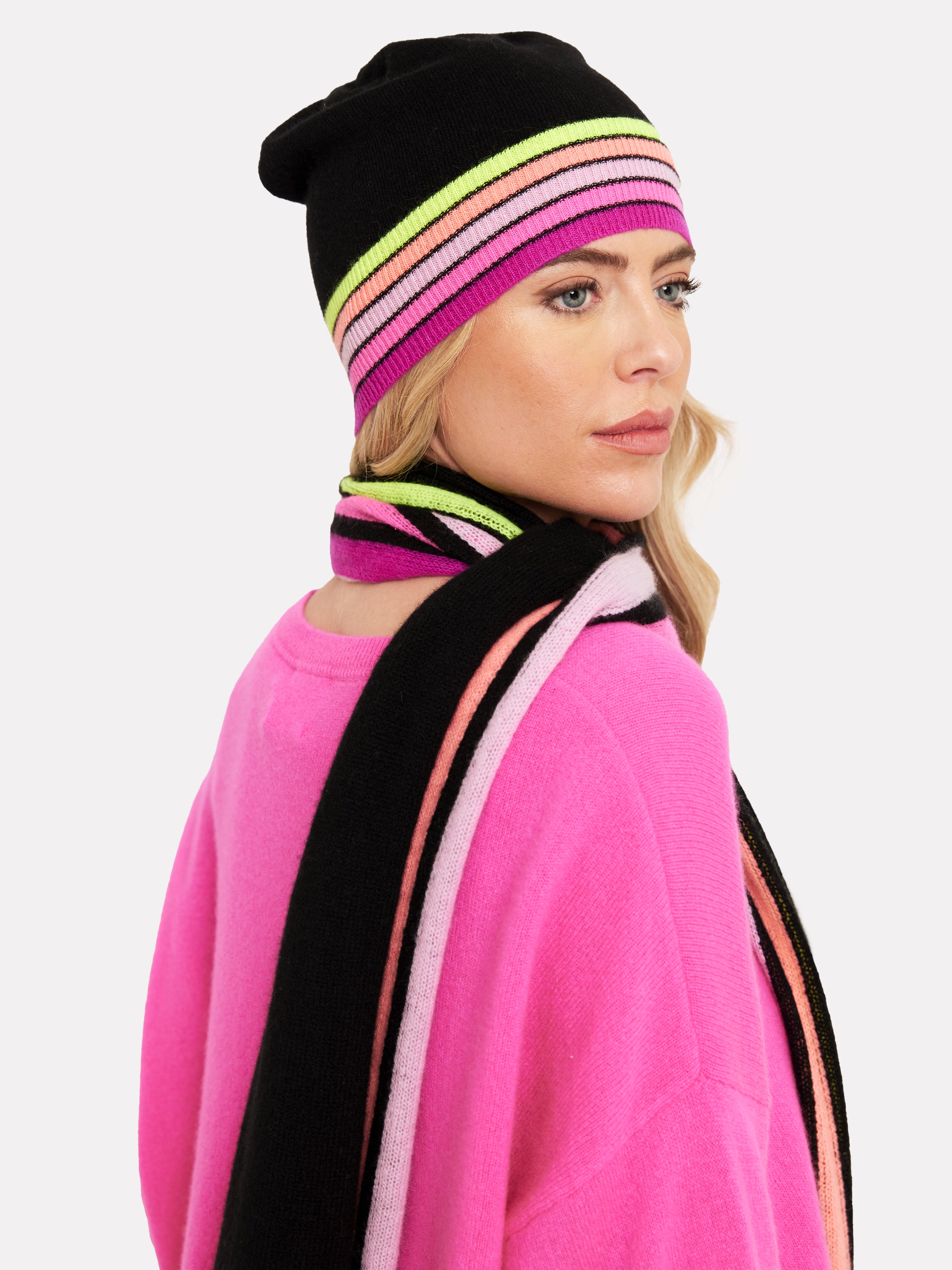 Woman wearing a black hat with rainbow multi colour trim and matching scarf