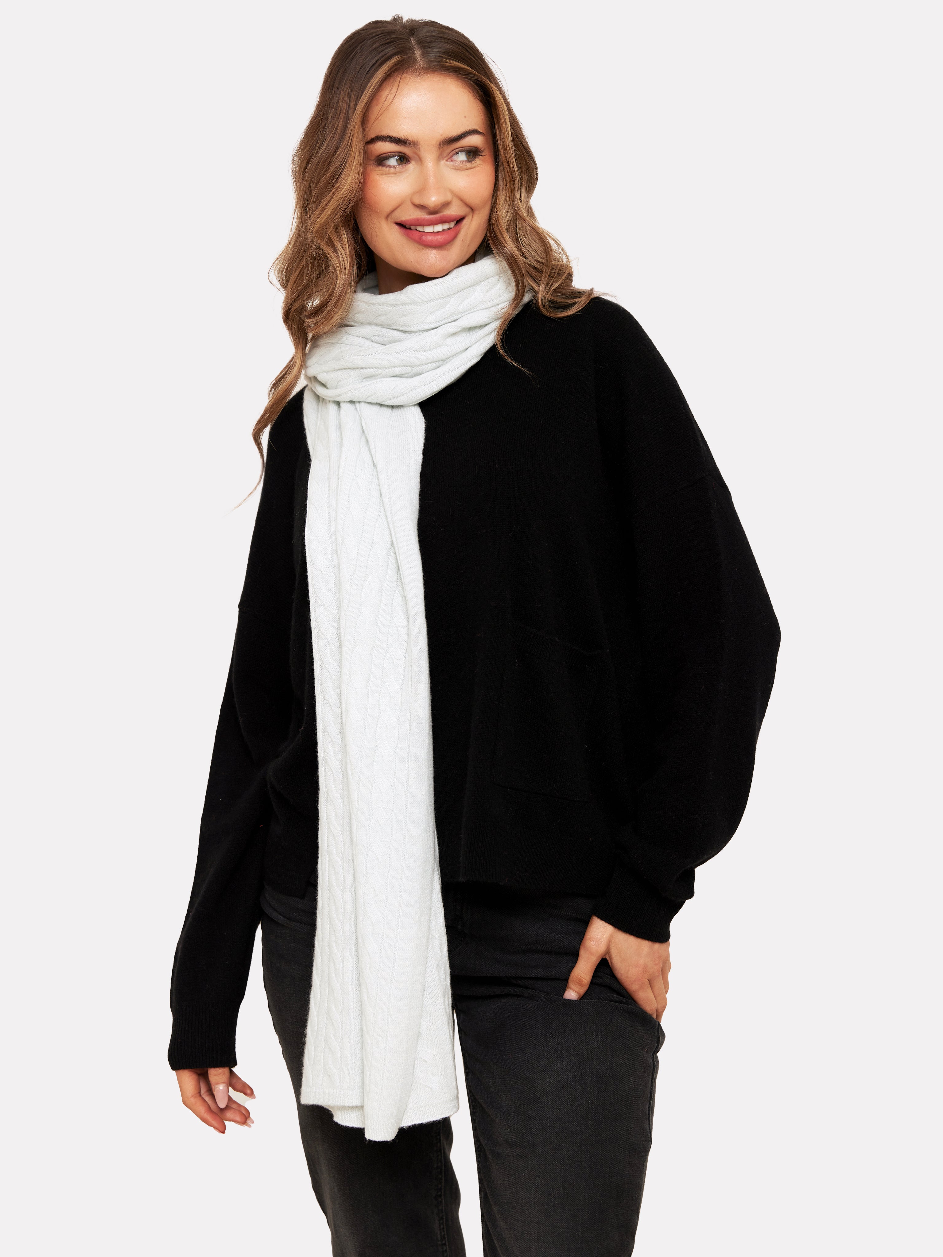 Woman wearing a pale blue cable knit scarf and black jumper