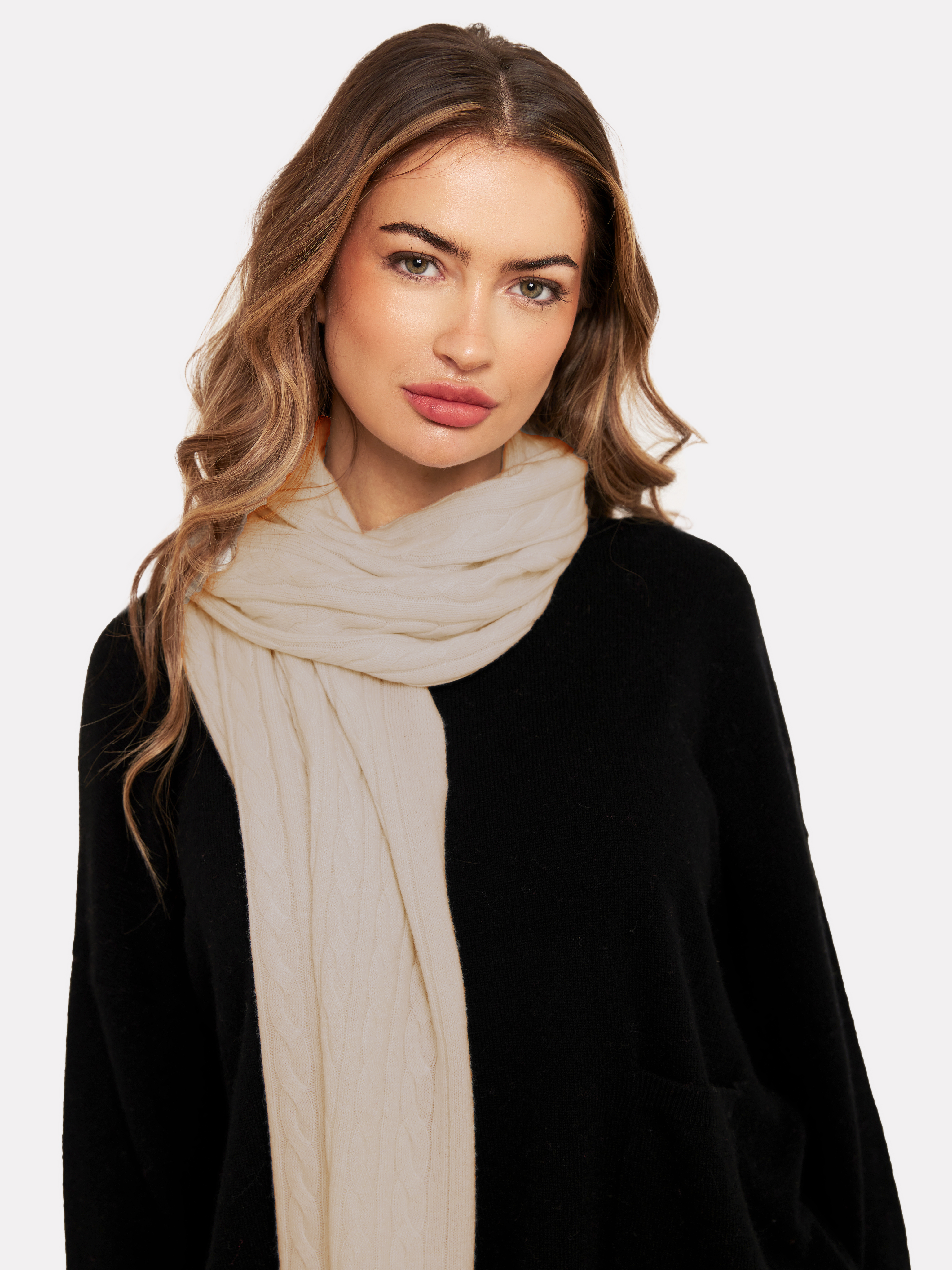 Woman wearing a light brown cable knit scarf and black jumper