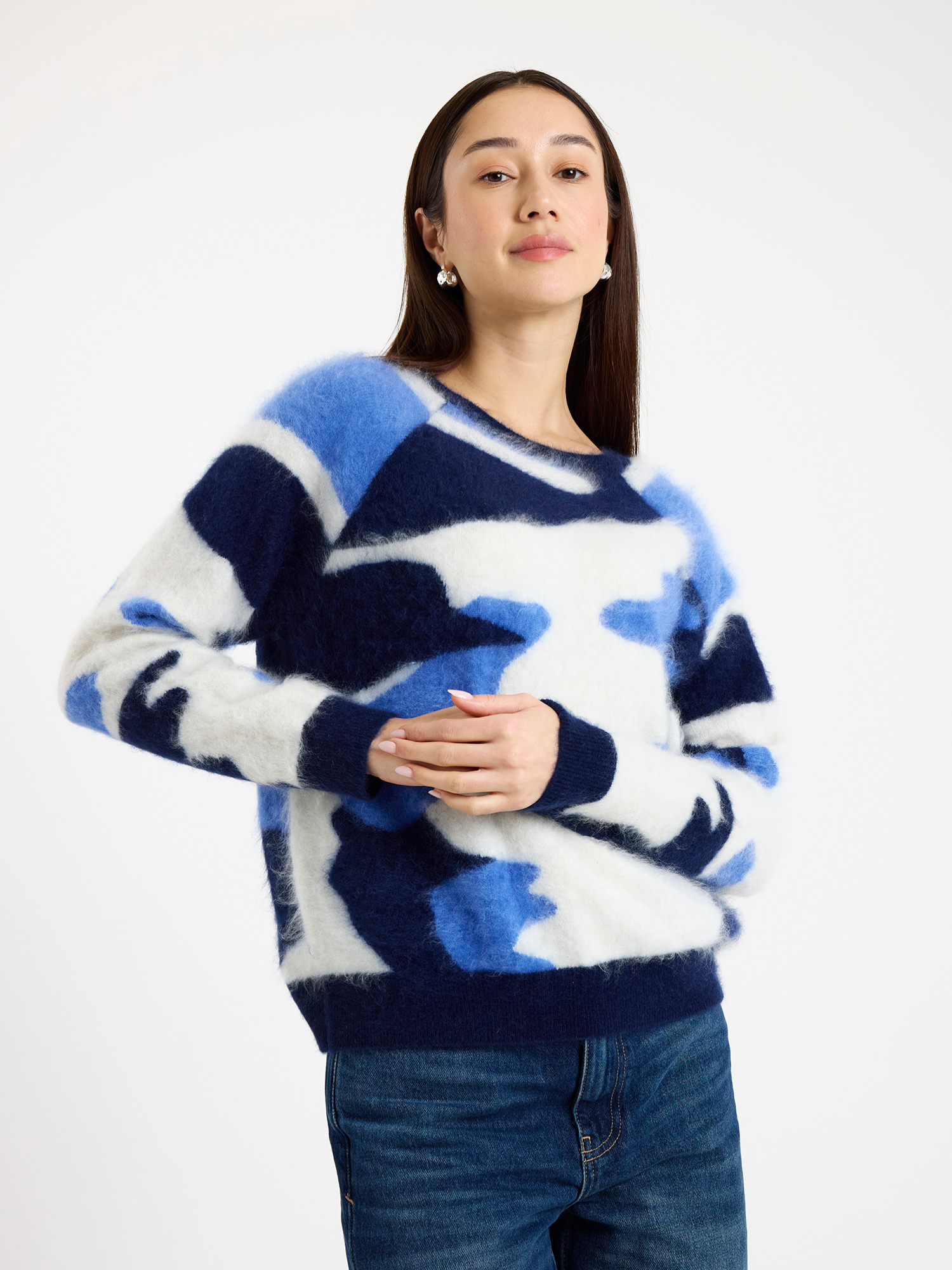 Woman wearing a blue and white camo patterned sweater on a white background