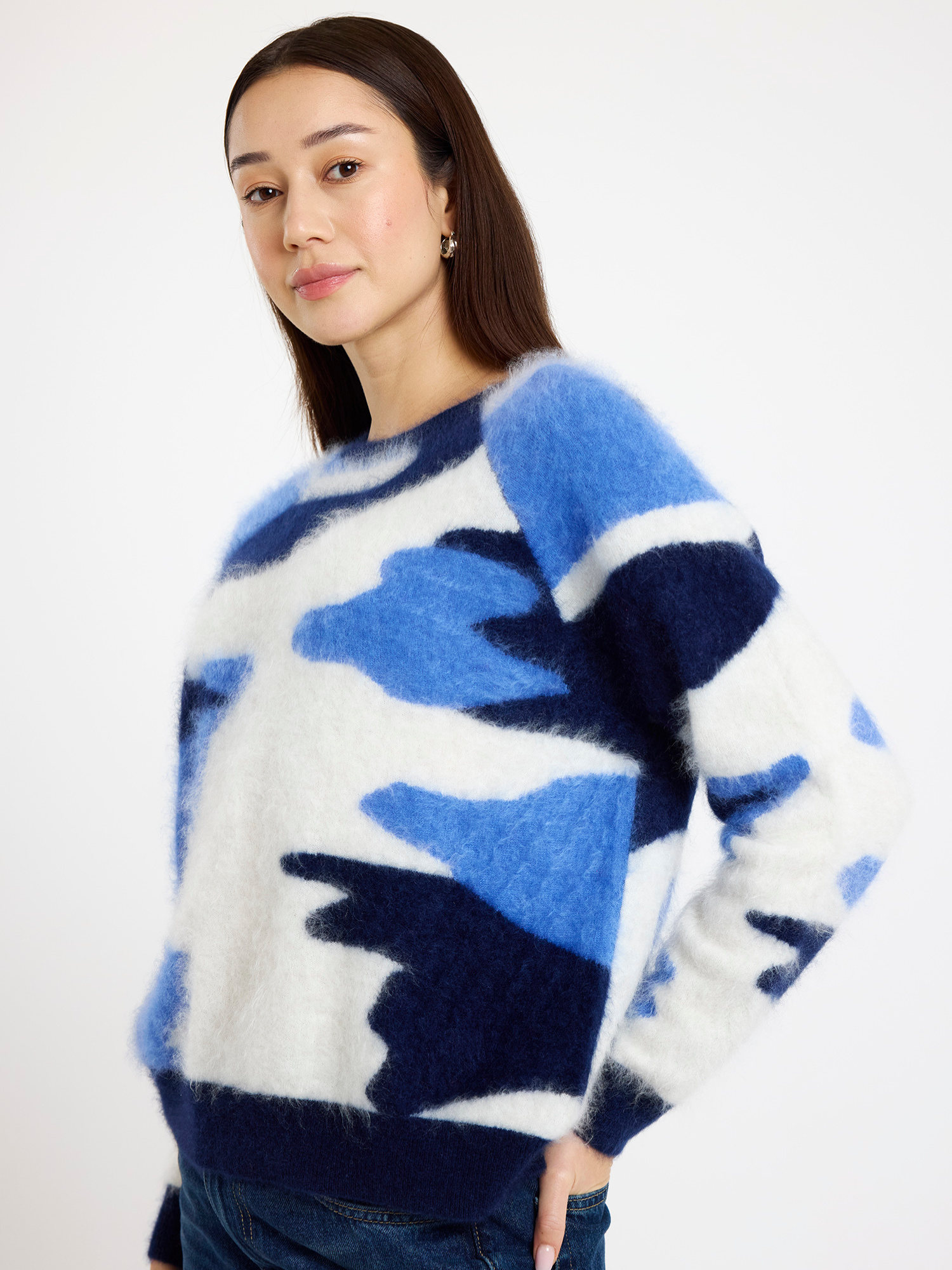 Woman wearing a blue and white camo patterned sweater against a plain background