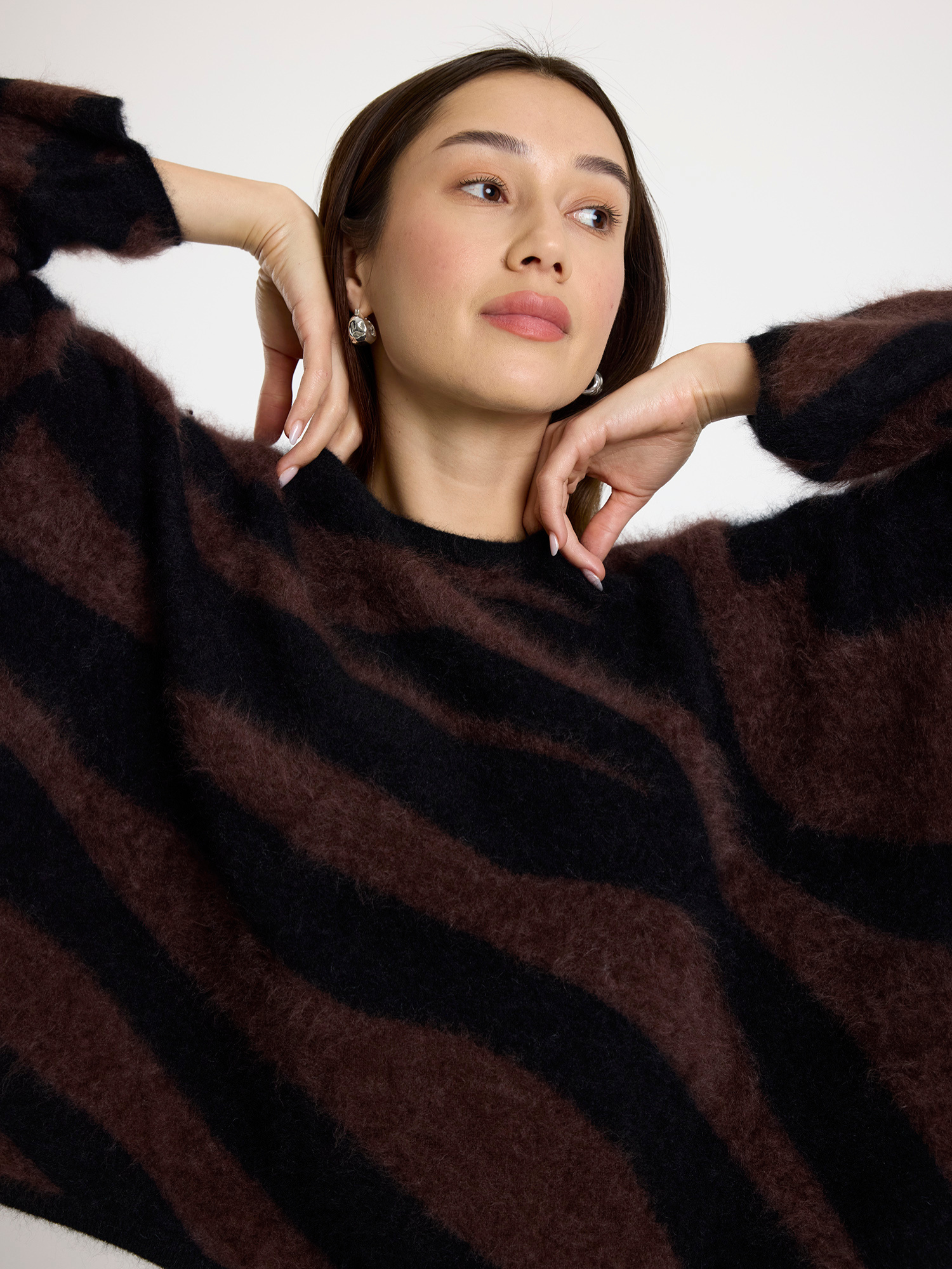Woman wearing a brown and black zebra striped sweater against a white background
