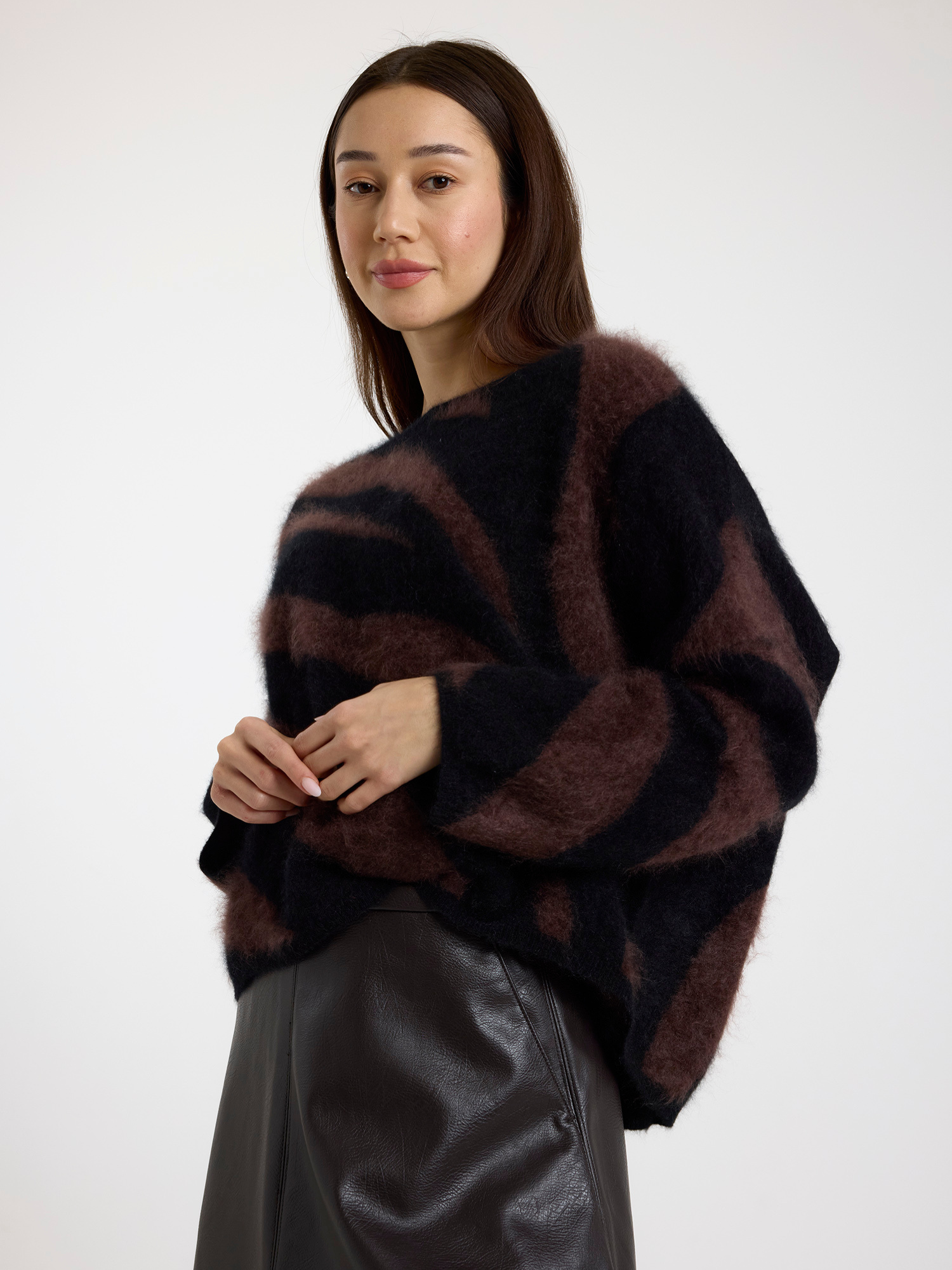 Woman wearing a brown and black zebra striped sweater with a brown leather skirt on a white background