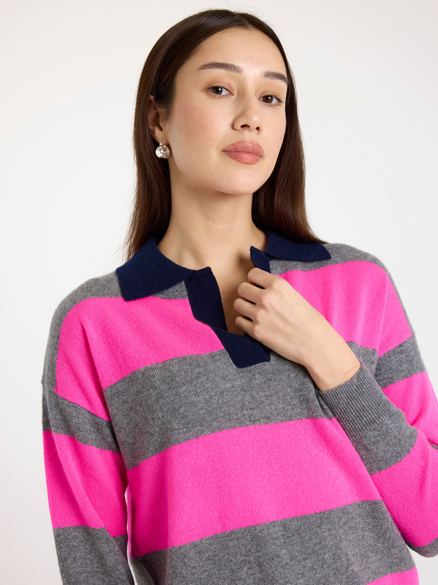 Woman wearing a pink and grey striped sweater with a white background