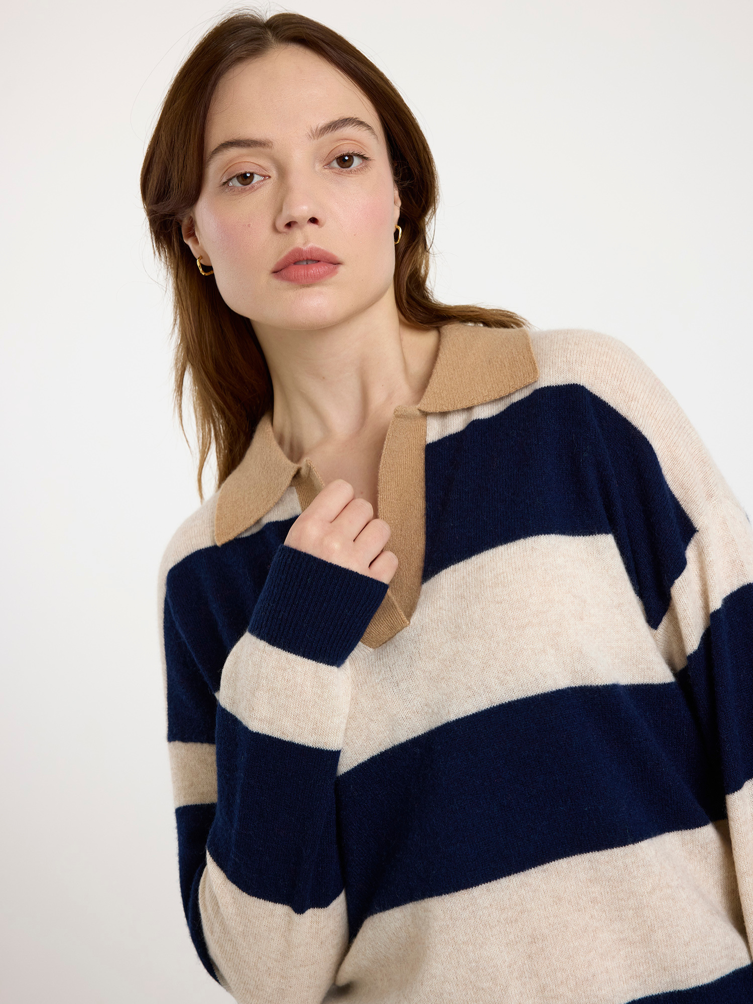 Woman wearing a navy and beige striped sweater with a white background