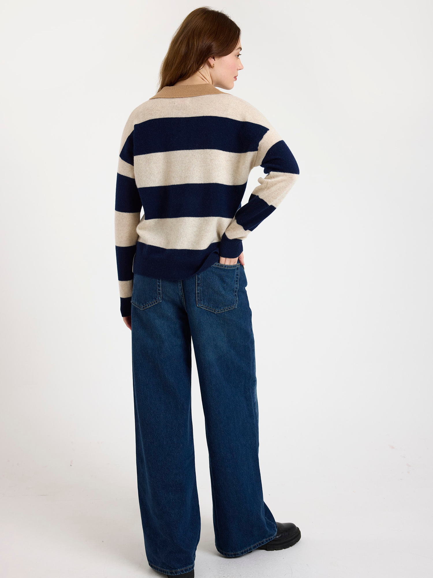Woman wearing a navy and beige striped sweater and jeans on a white background