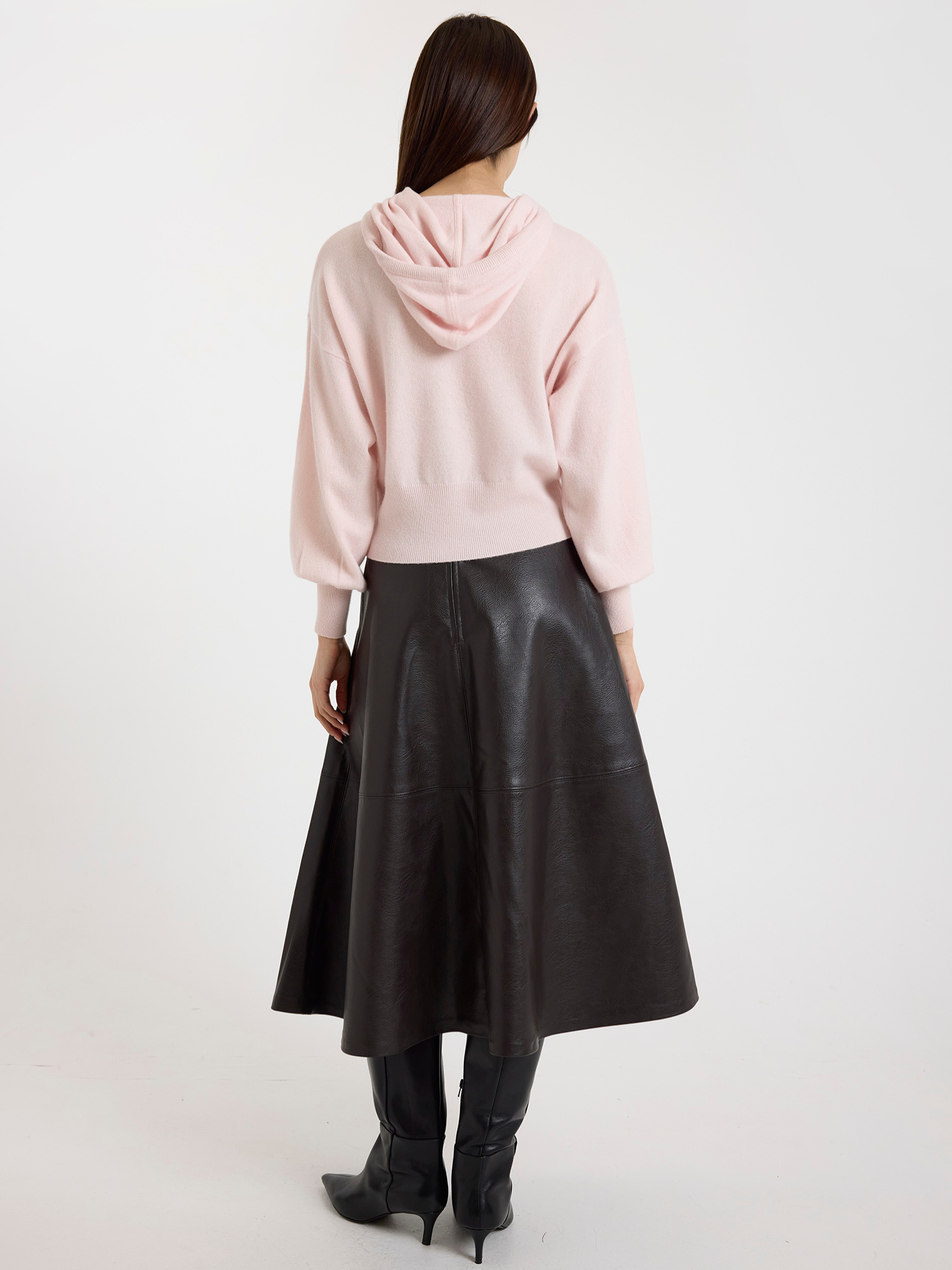 Woman wearing a pink hoodie and brown leather skirt on a white background