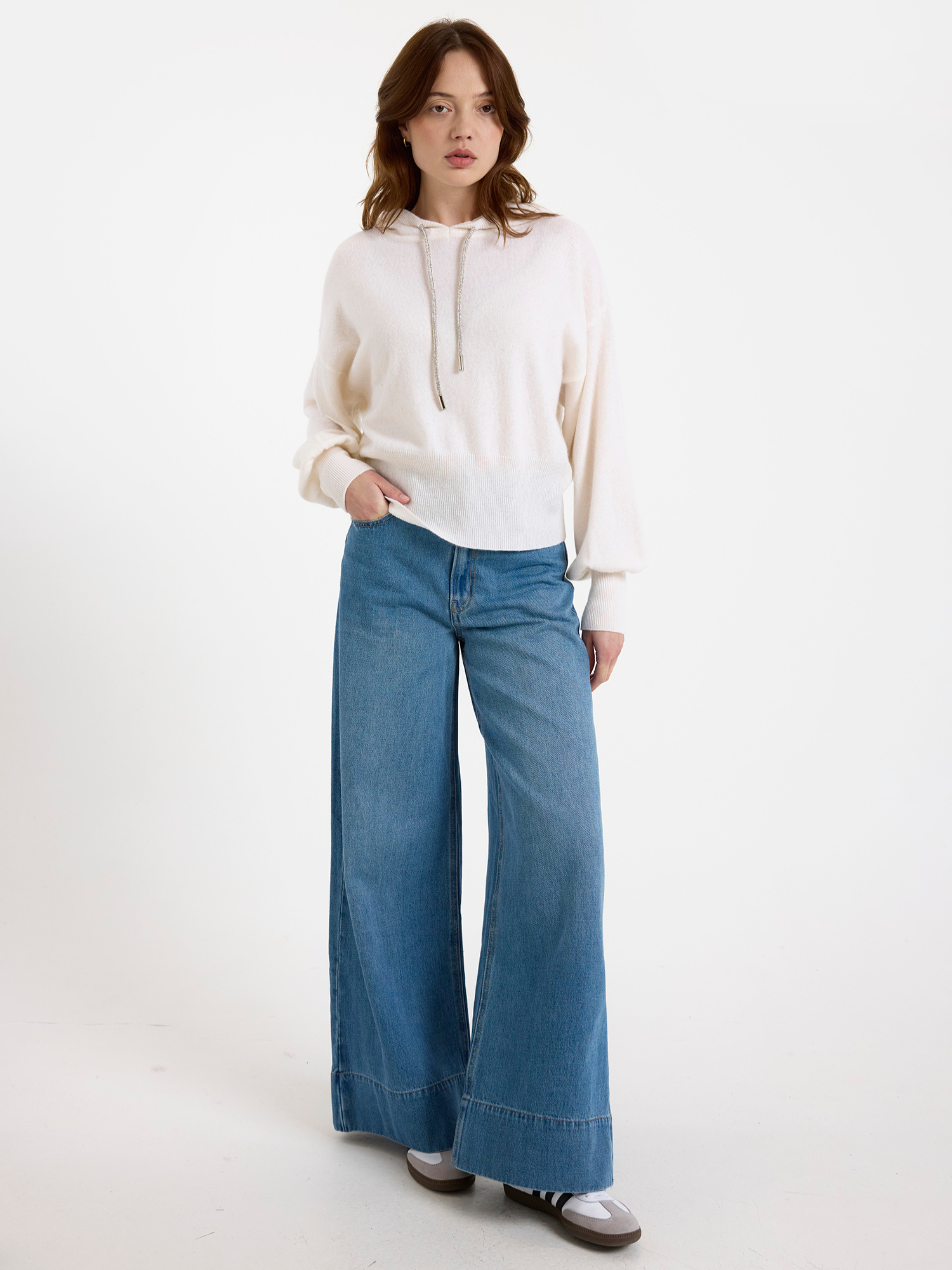 Woman wearing a white hoodie and blue jeans on a white background